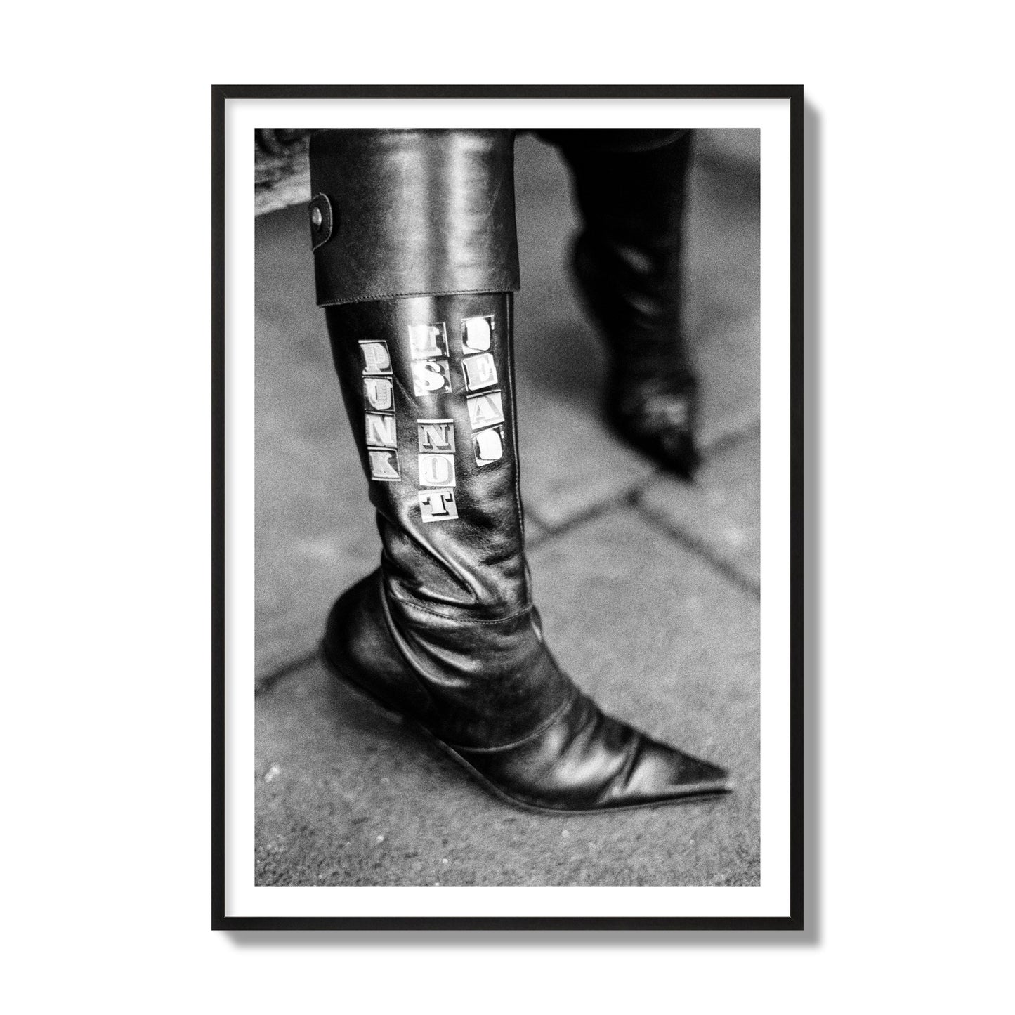 Fine art black and white photo of a woman's black leather boot with the words Punk is Not Dead, archival pigment print, collector size, black frame.