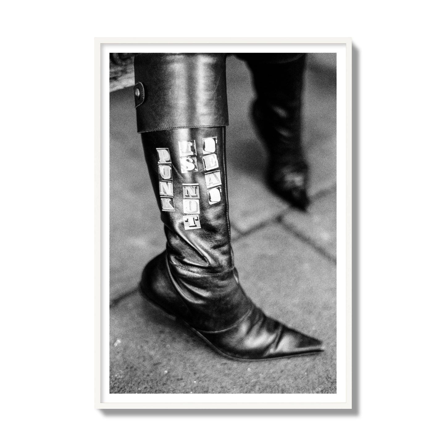 Fine art black and white photo of a woman's black leather boot with the words Punk is Not Dead, archival pigment print, collector size, white frame.