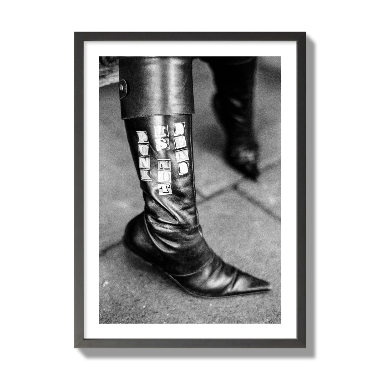 Fine art black and white photo of a woman's black leather boot with the words Punk is Not Dead, archival pigment print, giant size, black frame.