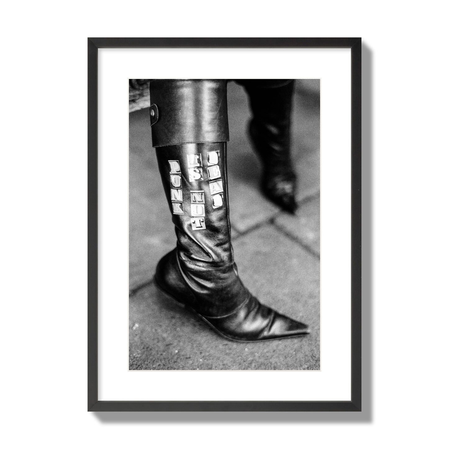 Fine art black and white photo of a woman's black leather boot with the words Punk is Not Dead, archival pigment print, large size, black frame.