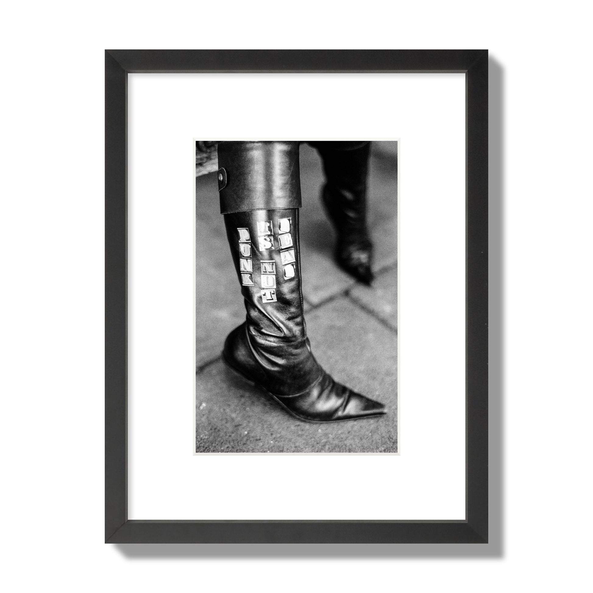 Fine art black and white photo of a woman's black leather boot with the words Punk is Not Dead, archival pigment print, small size, black frame.