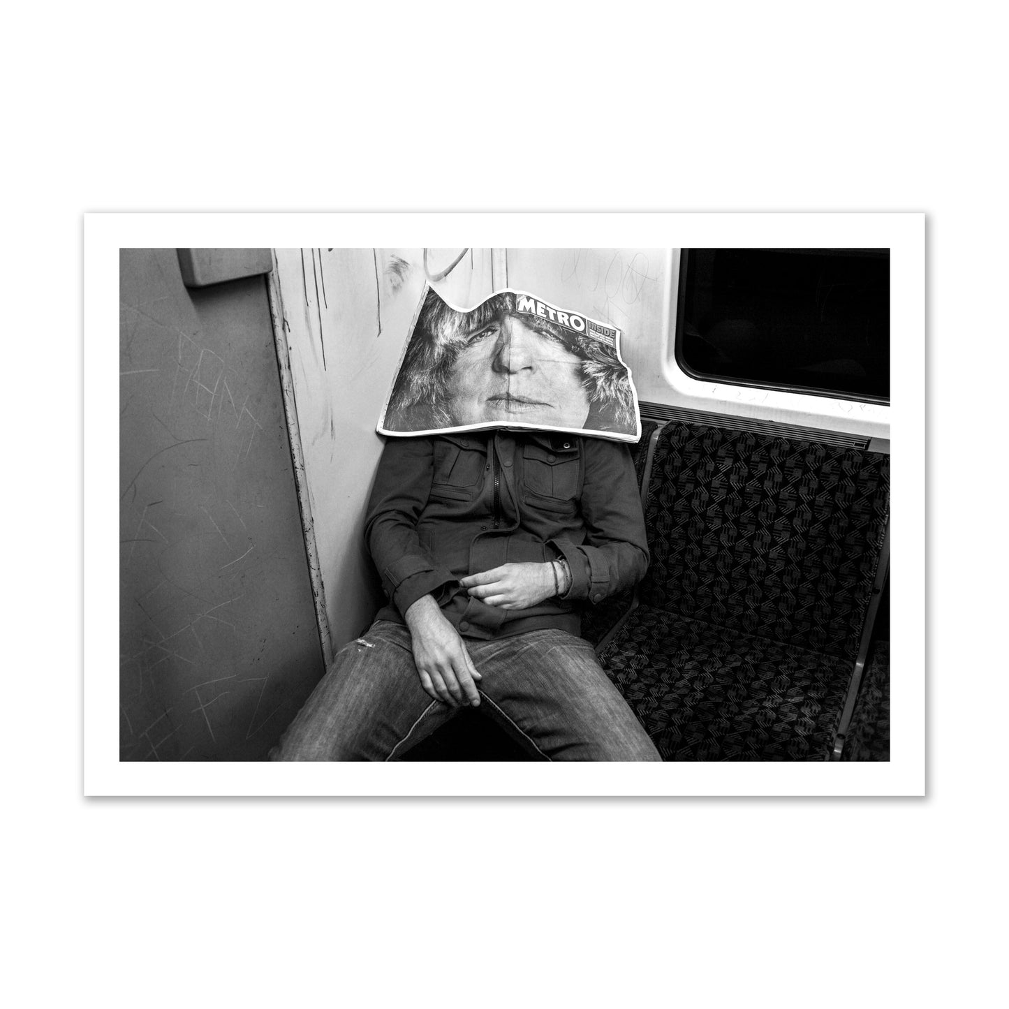 Fine art photograph of a man asleep on the subway with a newspaper covering their face, archival pigment print, gallery size, unframed.