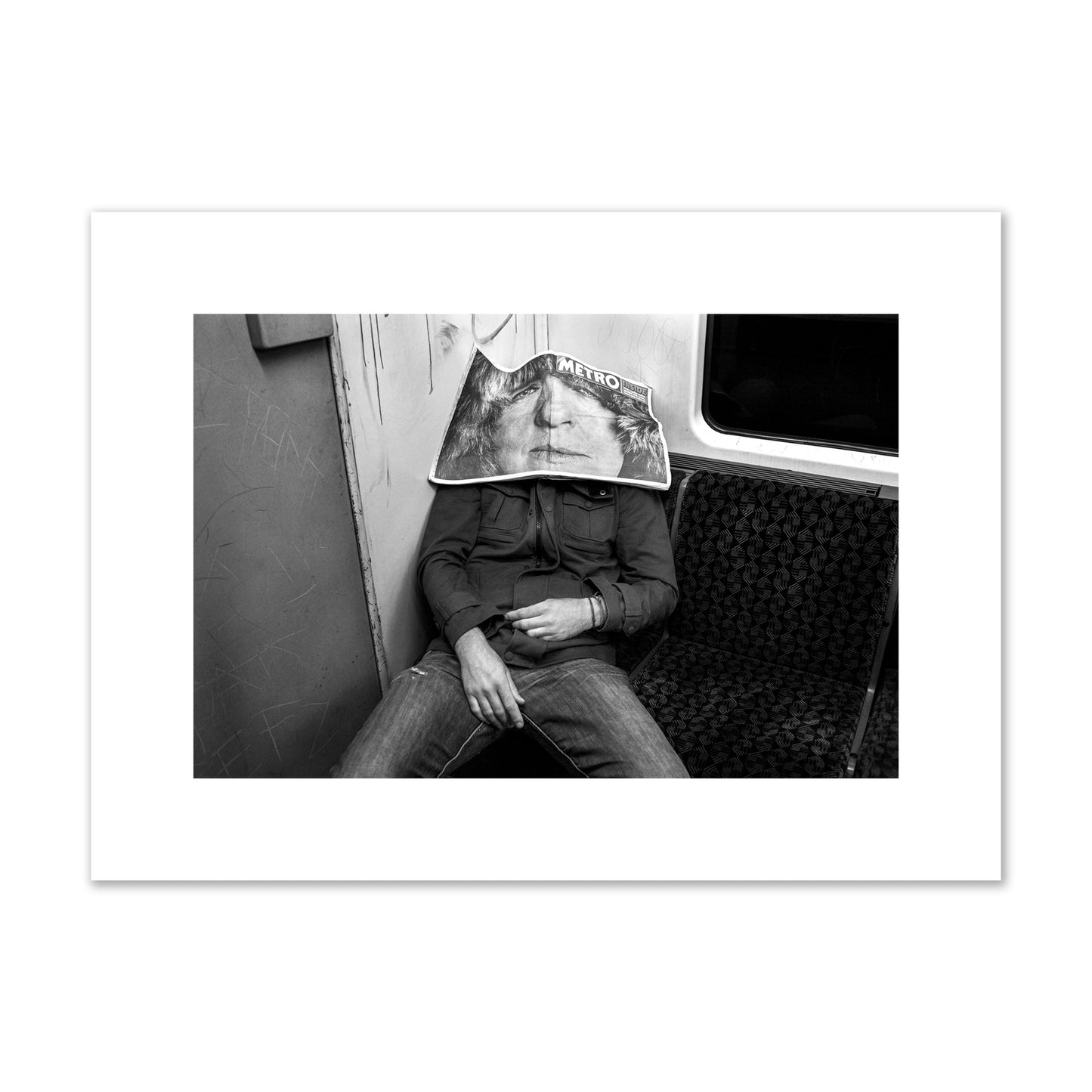 Fine art photograph of a man asleep on the subway with a newspaper covering their face, archival pigment print, medium size, unframed.