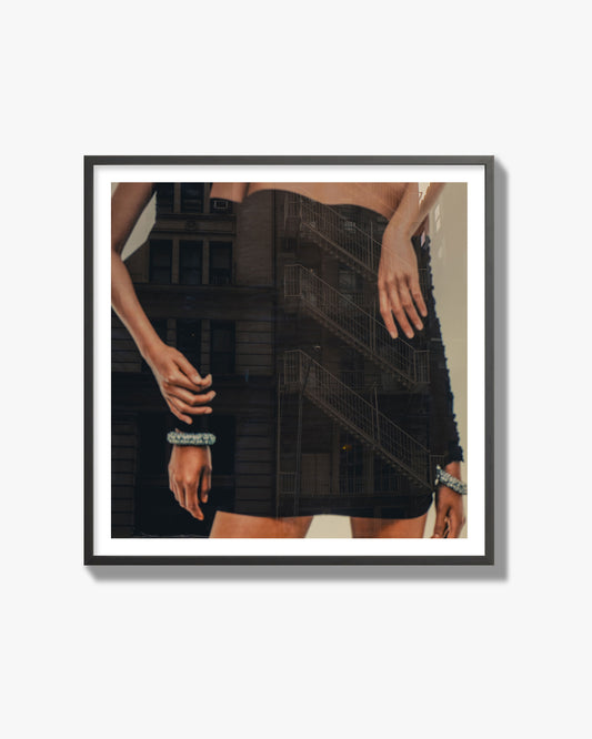 Fine art photograph of two women in black dresses, with the pattern of a fire escape reflected across the fabric, archival pigment print, black frame.