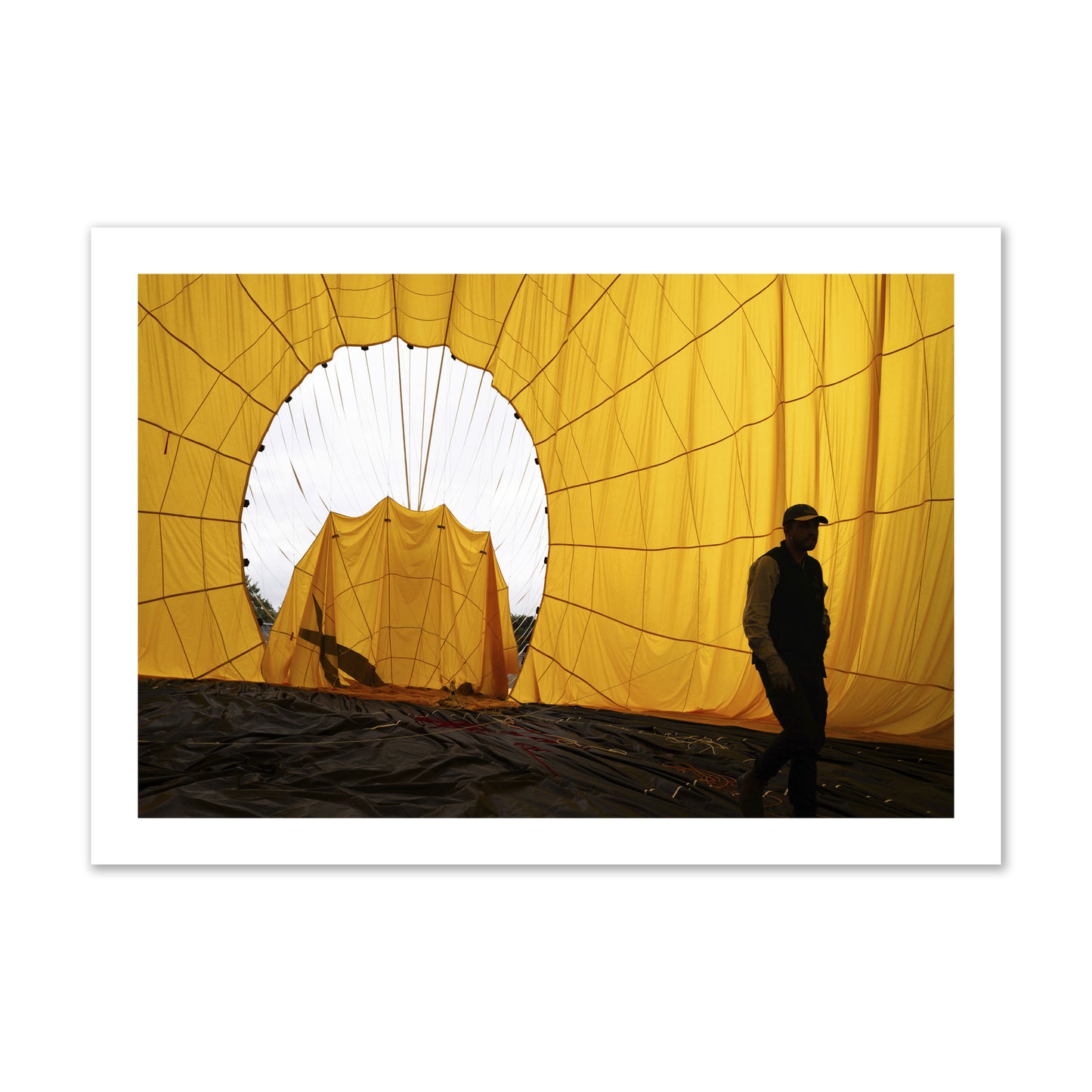 Fine art photograph of a man walking inside a bright yellow hot air balloon as it slowly deflates. Archival pigment print, collector size, unframed.