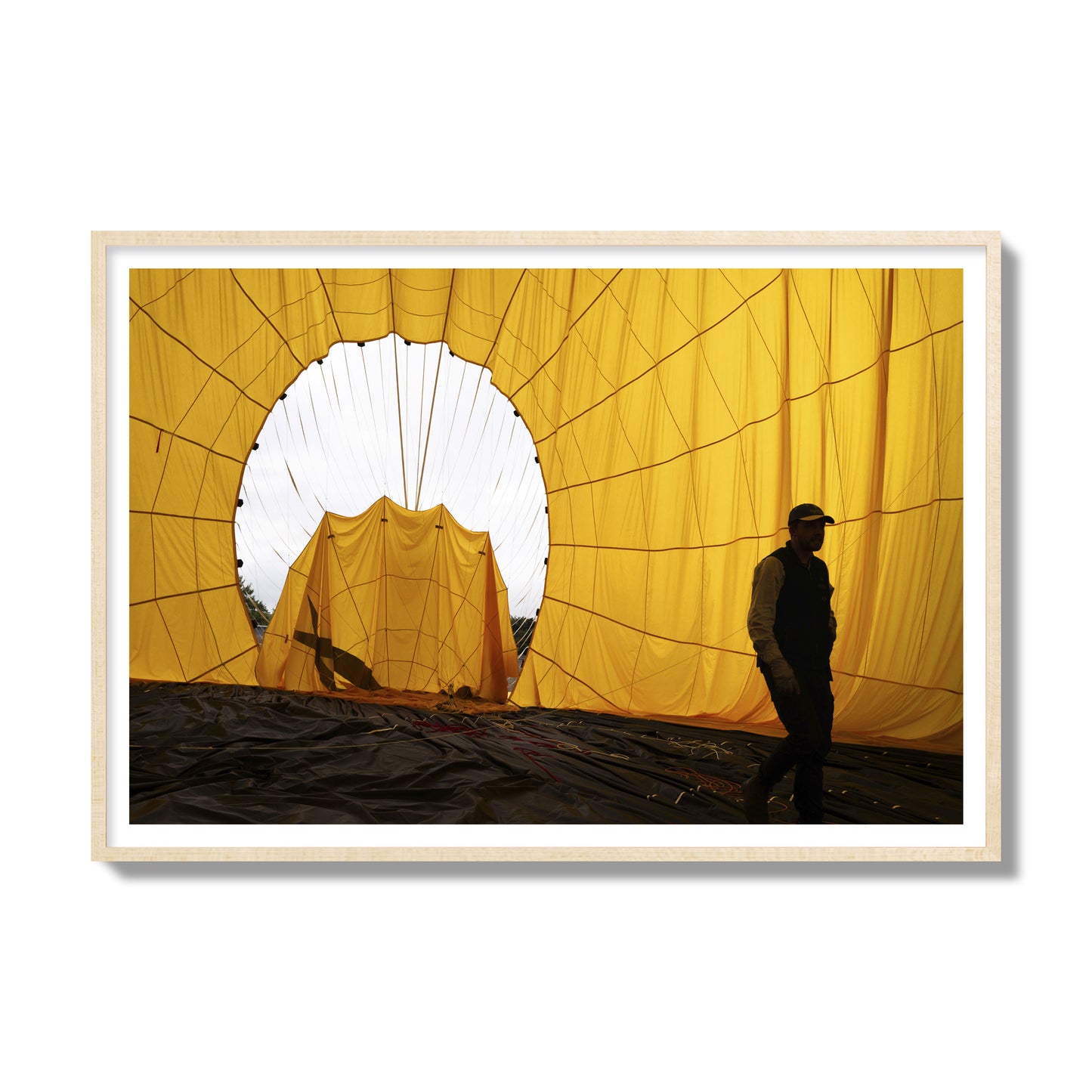 Fine art photograph of a man walking inside a bright yellow hot air balloon as it slowly deflates. Archival pigment print, gallery size, natural wood frame.