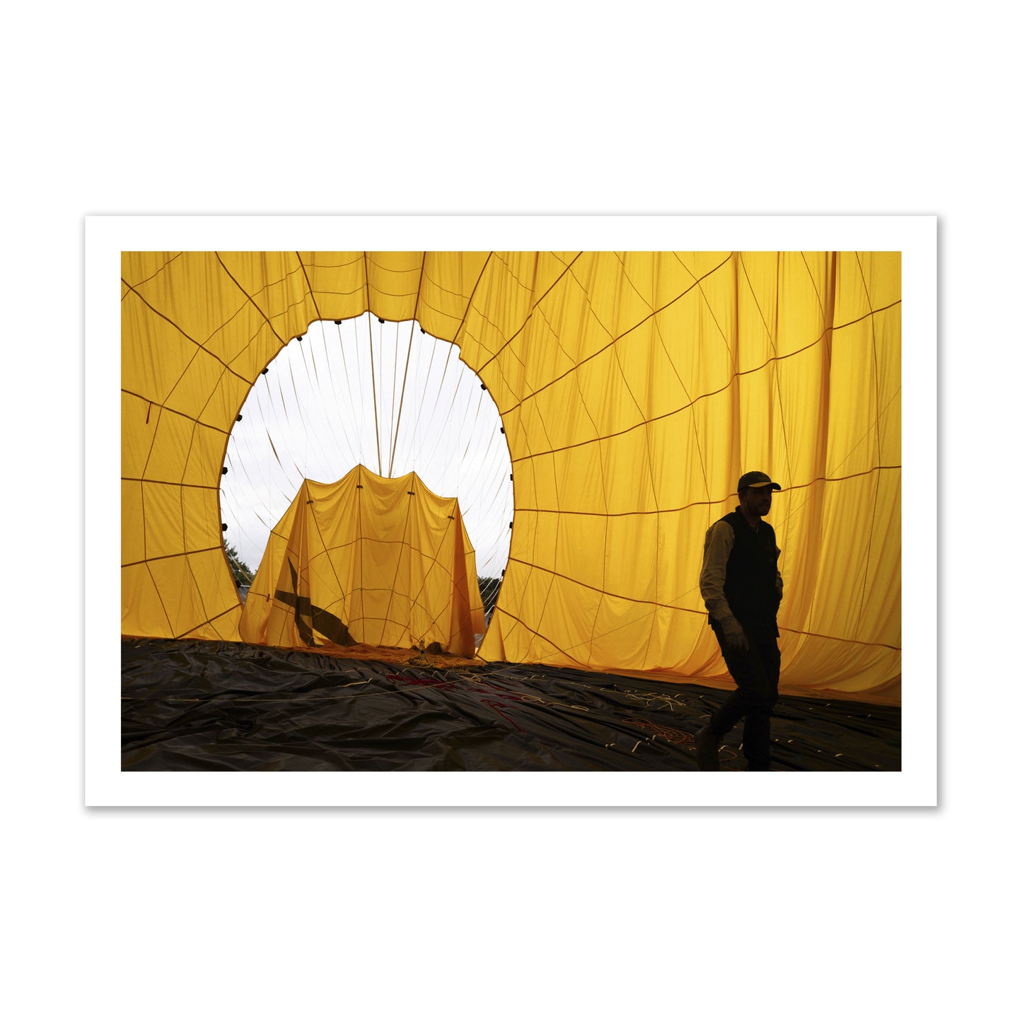 Fine art photograph of a man walking inside a bright yellow hot air balloon as it slowly deflates. Archival pigment print, gallery size, unframed.