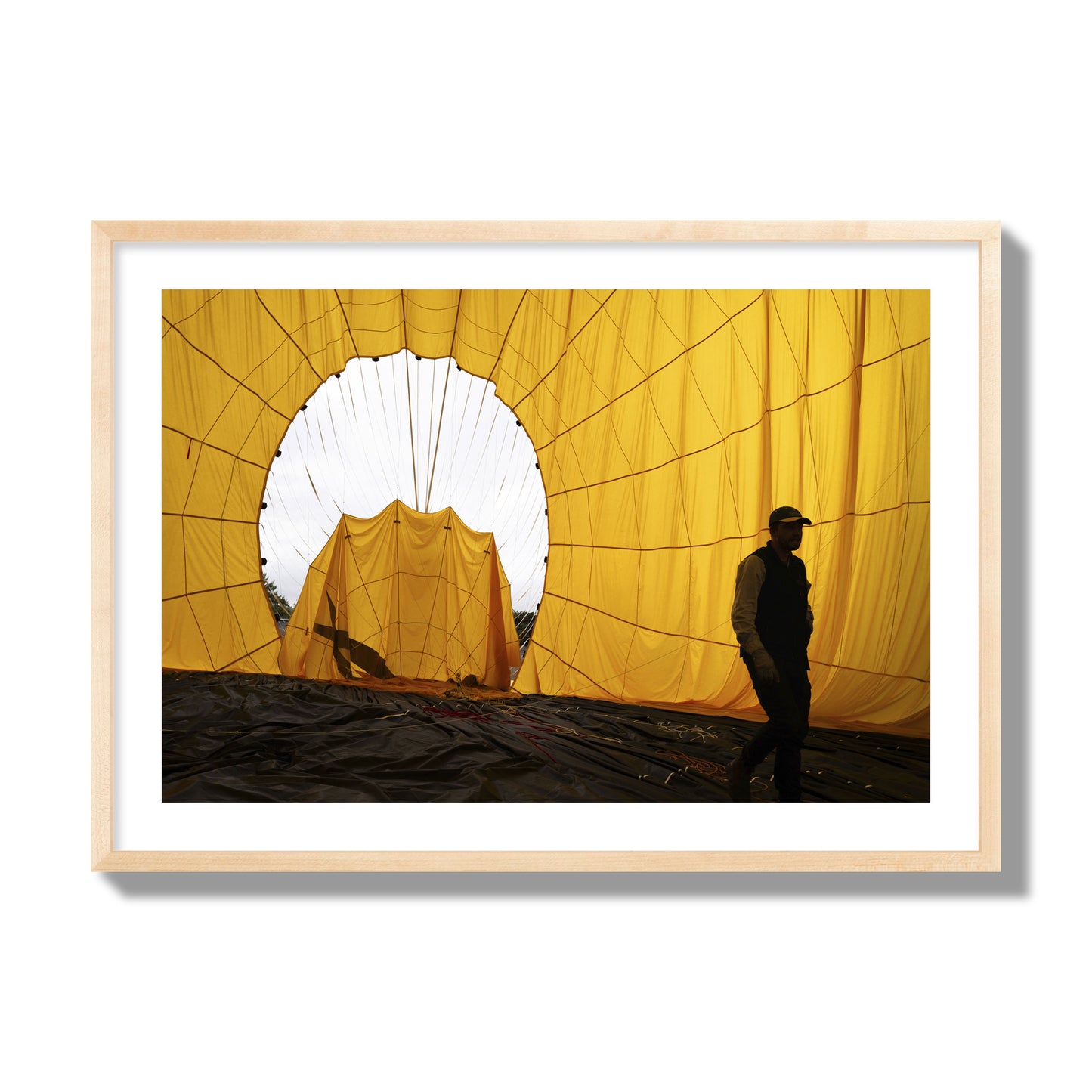 Fine art photograph of a man walking inside a bright yellow hot air balloon as it slowly deflates. Archival pigment print, giant size, natural wood frame.