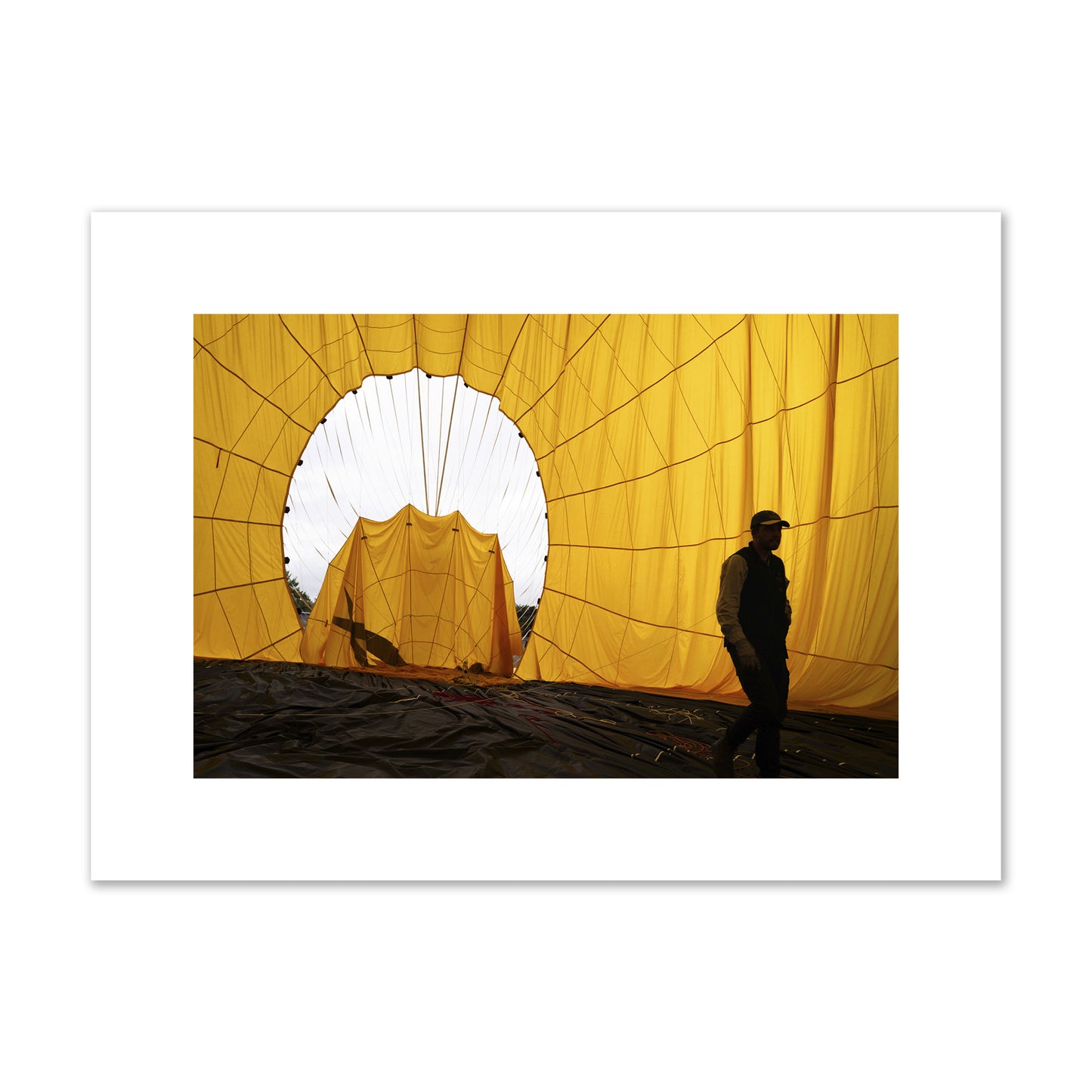 Fine art photograph of a man walking inside a bright yellow hot air balloon as it slowly deflates. Archival pigment print, medium size, unframed.
