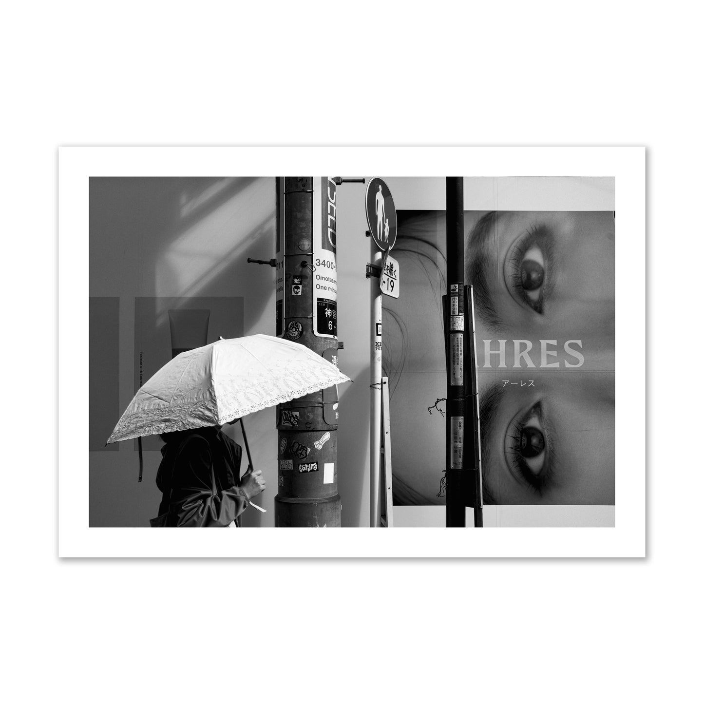 Fine art street photograph of a woman walking with an umbrella on a Tokyo street, passing beneath a billboard with two large eyes. Archival pigment print, collector size, unframed.