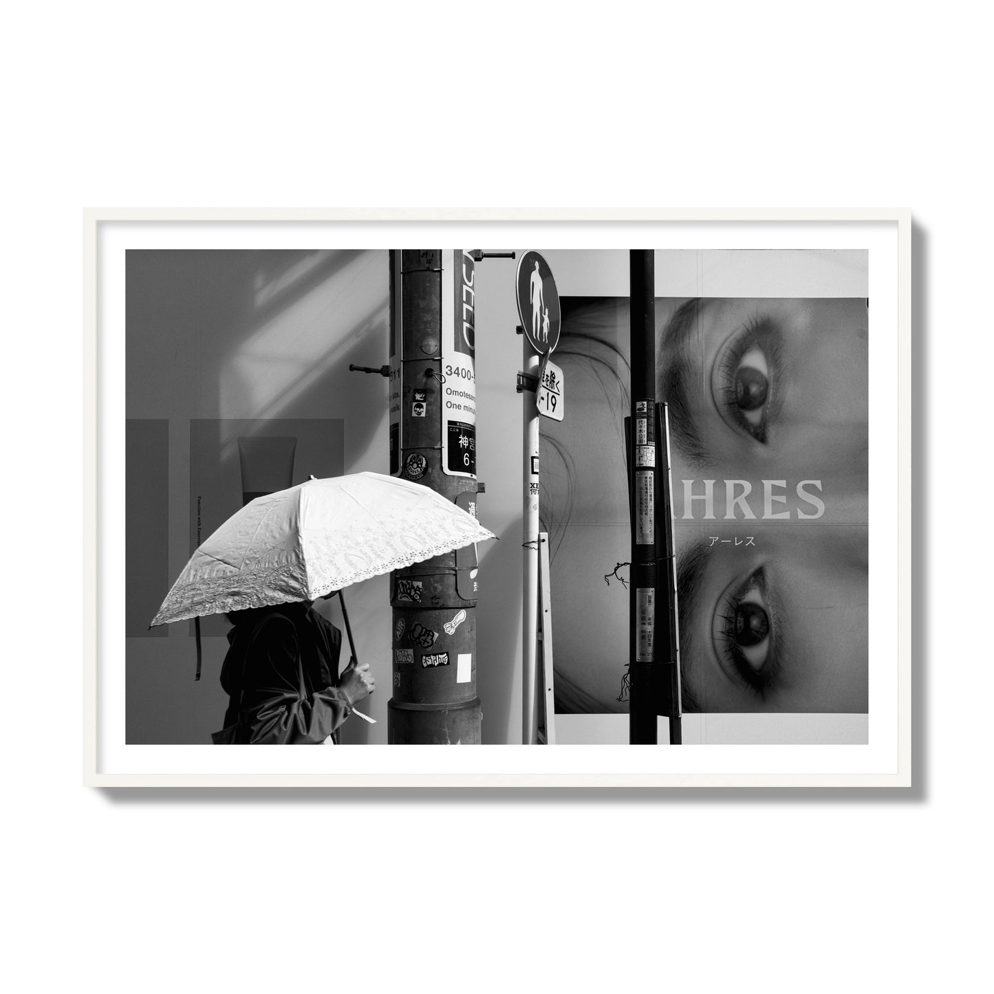 Fine art street photograph of a woman walking with an umbrella on a Tokyo street, passing beneath a billboard with two large eyes. Archival pigment print, collector size, white frame.