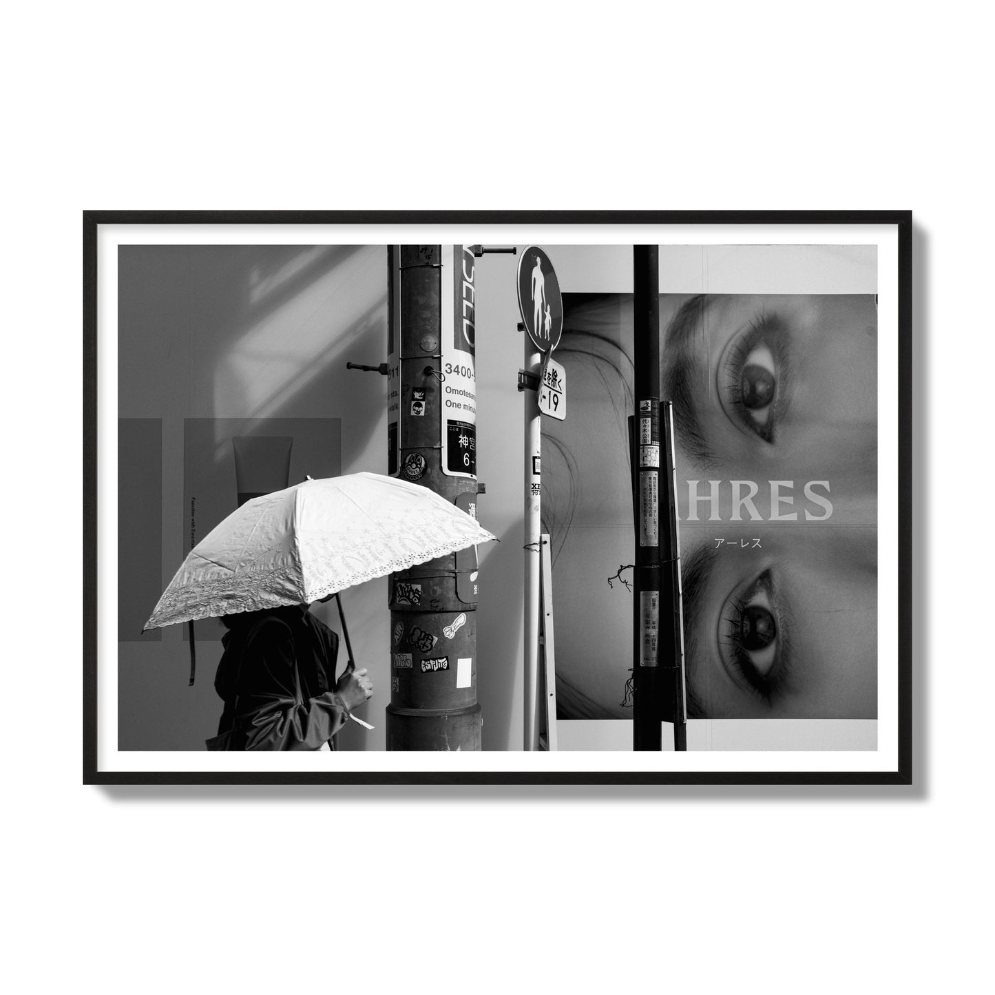 Fine art street photograph of a woman walking with an umbrella on a Tokyo street, passing beneath a billboard with two large eyes. Archival pigment print, gallery size, black frame.