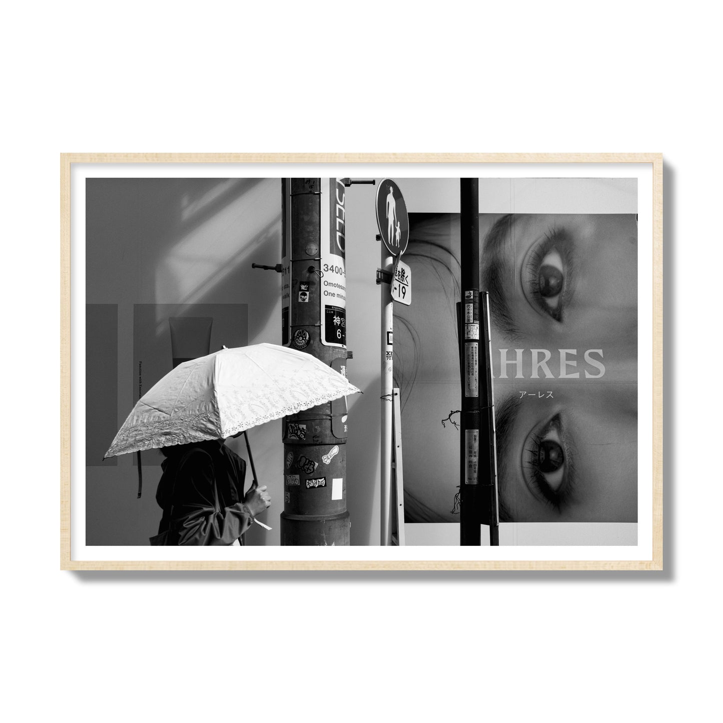 Fine art street photograph of a woman walking with an umbrella on a Tokyo street, passing beneath a billboard with two large eyes. Archival pigment print, gallery size, natural wood frame.