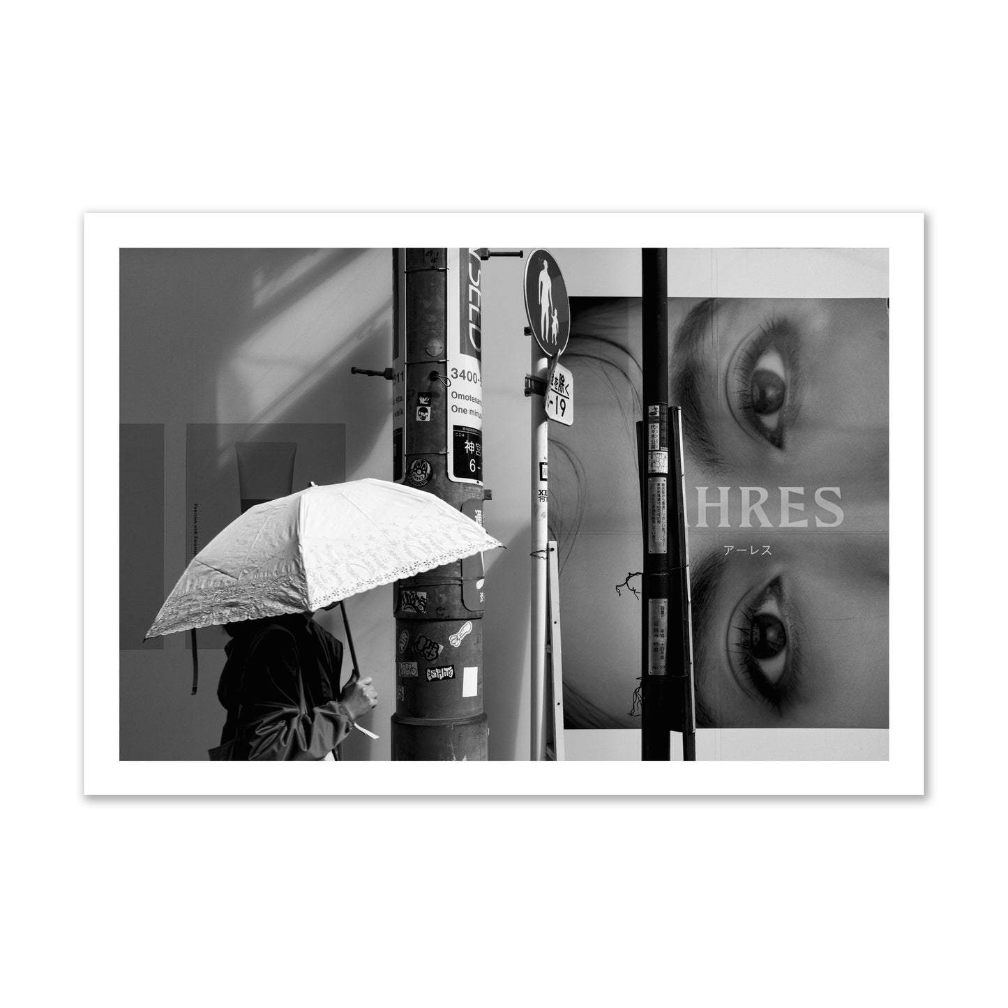 Fine art street photograph of a woman walking with an umbrella on a Tokyo street, passing beneath a billboard with two large eyes. Archival pigment print, gallery size, unframed.