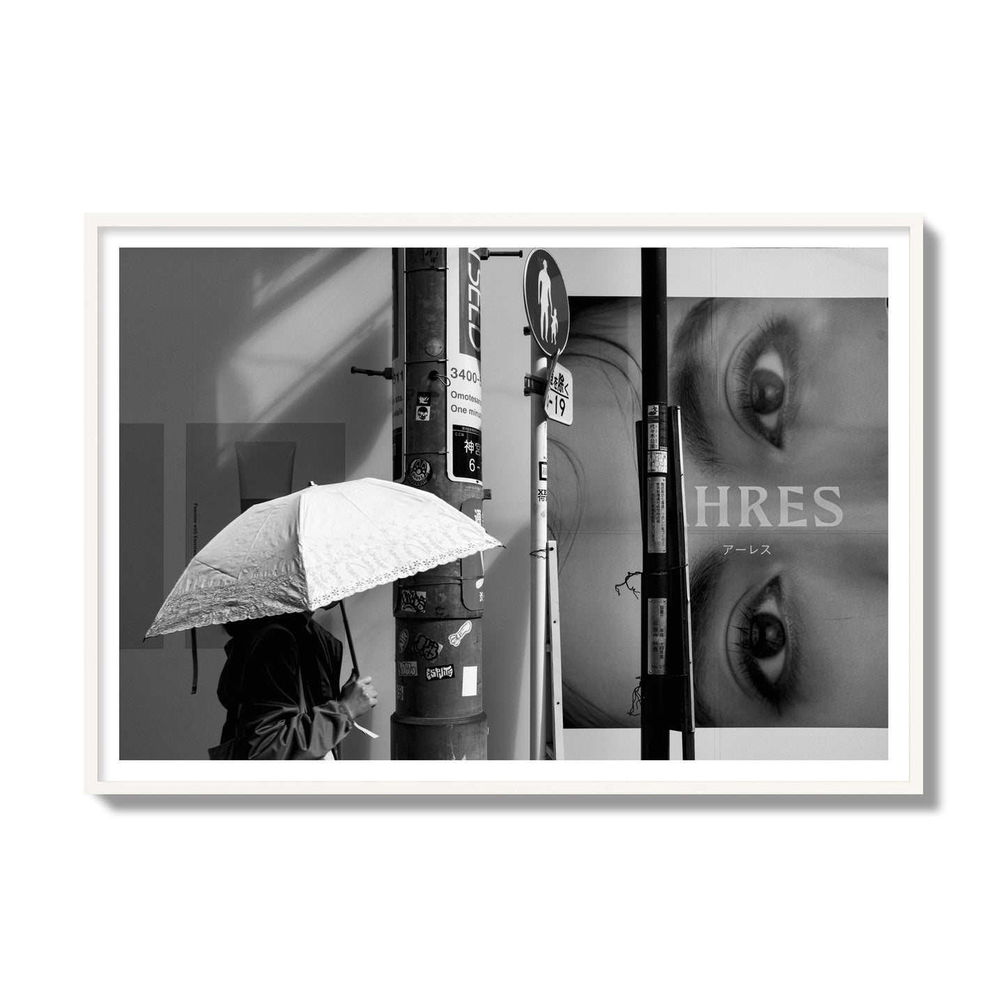 Fine art street photograph of a woman walking with an umbrella on a Tokyo street, passing beneath a billboard with two large eyes. Archival pigment print, gallery size, white frame.