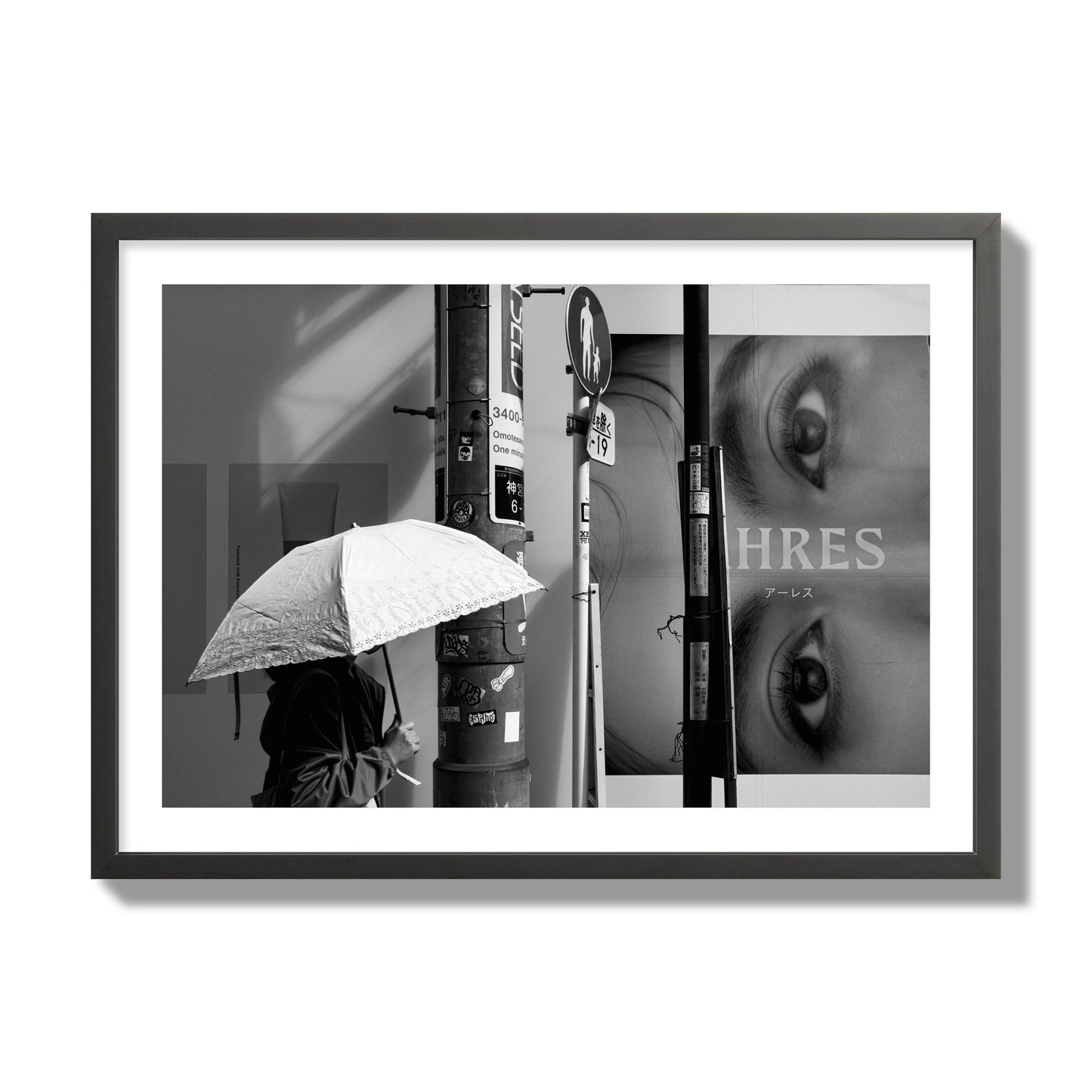 Fine art street photograph of a woman walking with an umbrella on a Tokyo street, passing beneath a billboard with two large eyes. Archival pigment print, giant size, black frame.