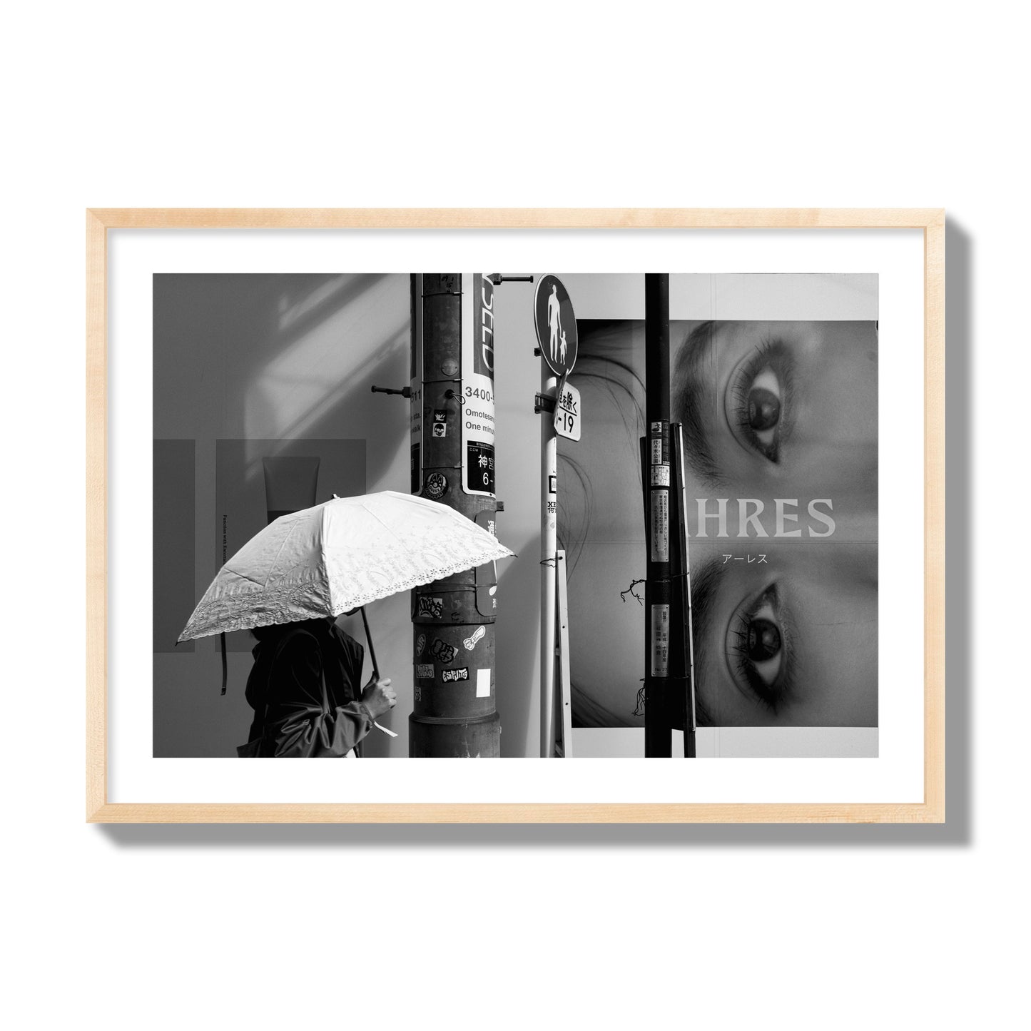 Fine art street photograph of a woman walking with an umbrella on a Tokyo street, passing beneath a billboard with two large eyes. Archival pigment print, giant size, natural wood frame.