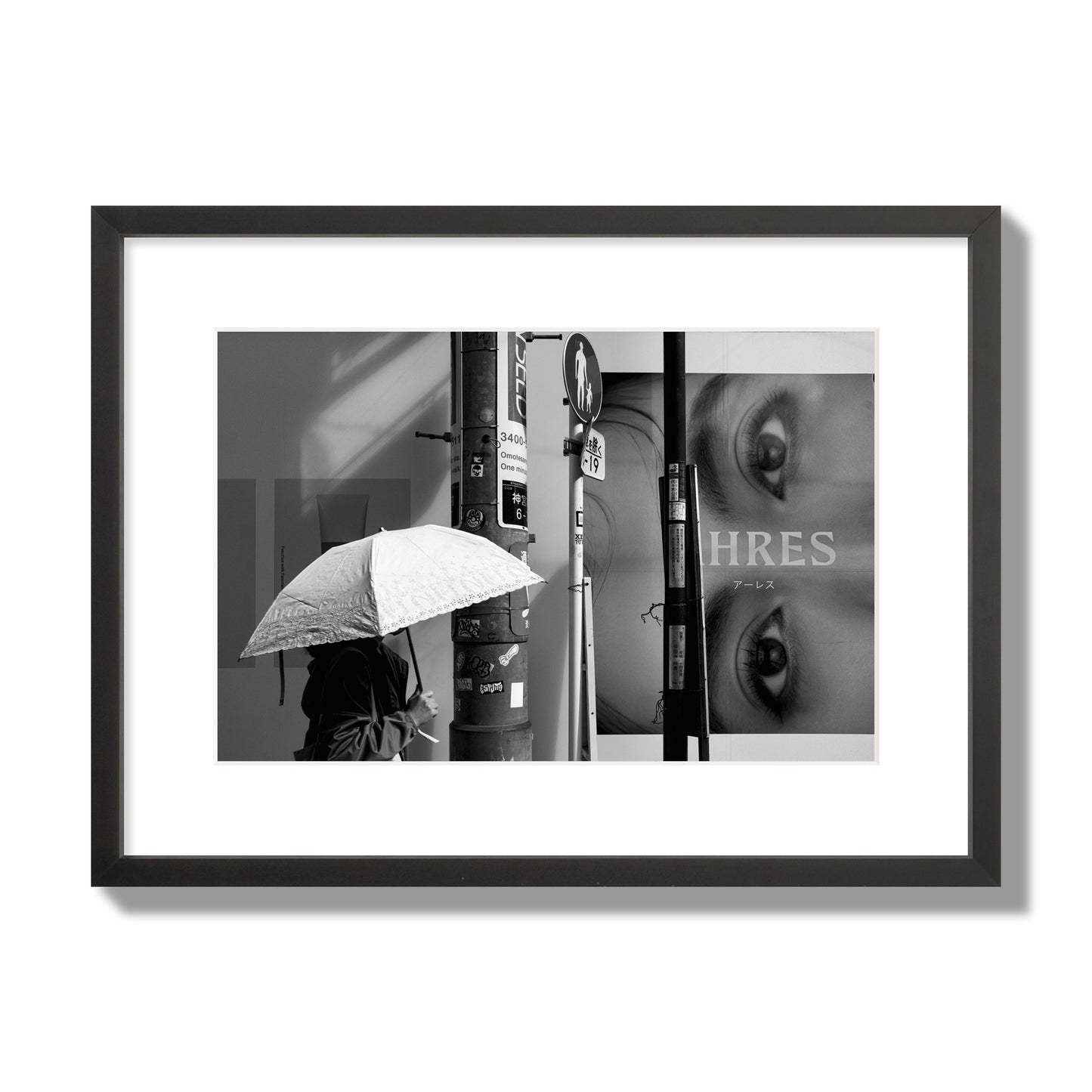 Fine art street photograph of a woman walking with an umbrella on a Tokyo street, passing beneath a billboard with two large eyes. Archival pigment print, medium size, black frame.