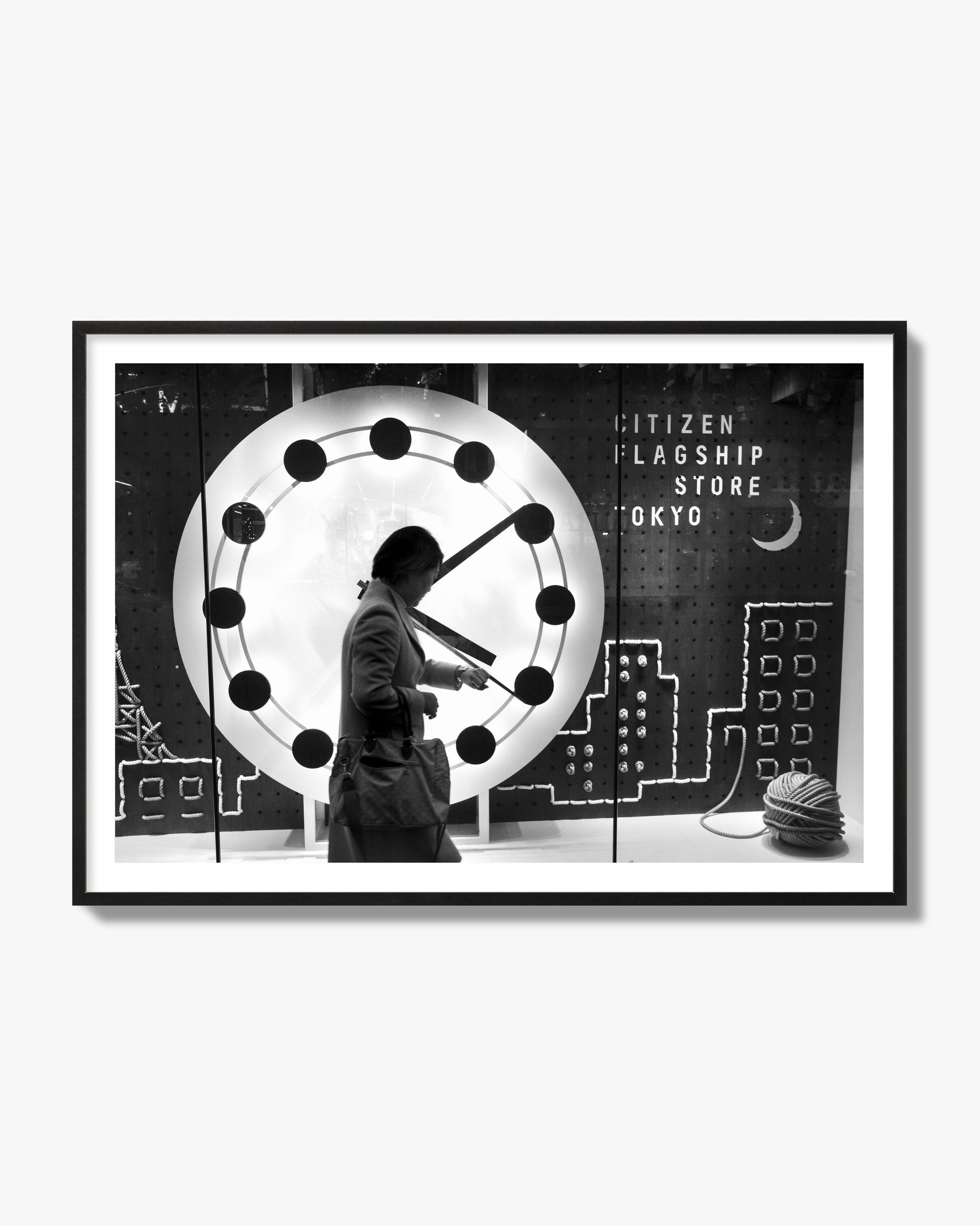 Fine art street photograph of a woman checking her watch as she walks past a giant clock on a busy Tokyo city street. Archival pigment print, black frame.