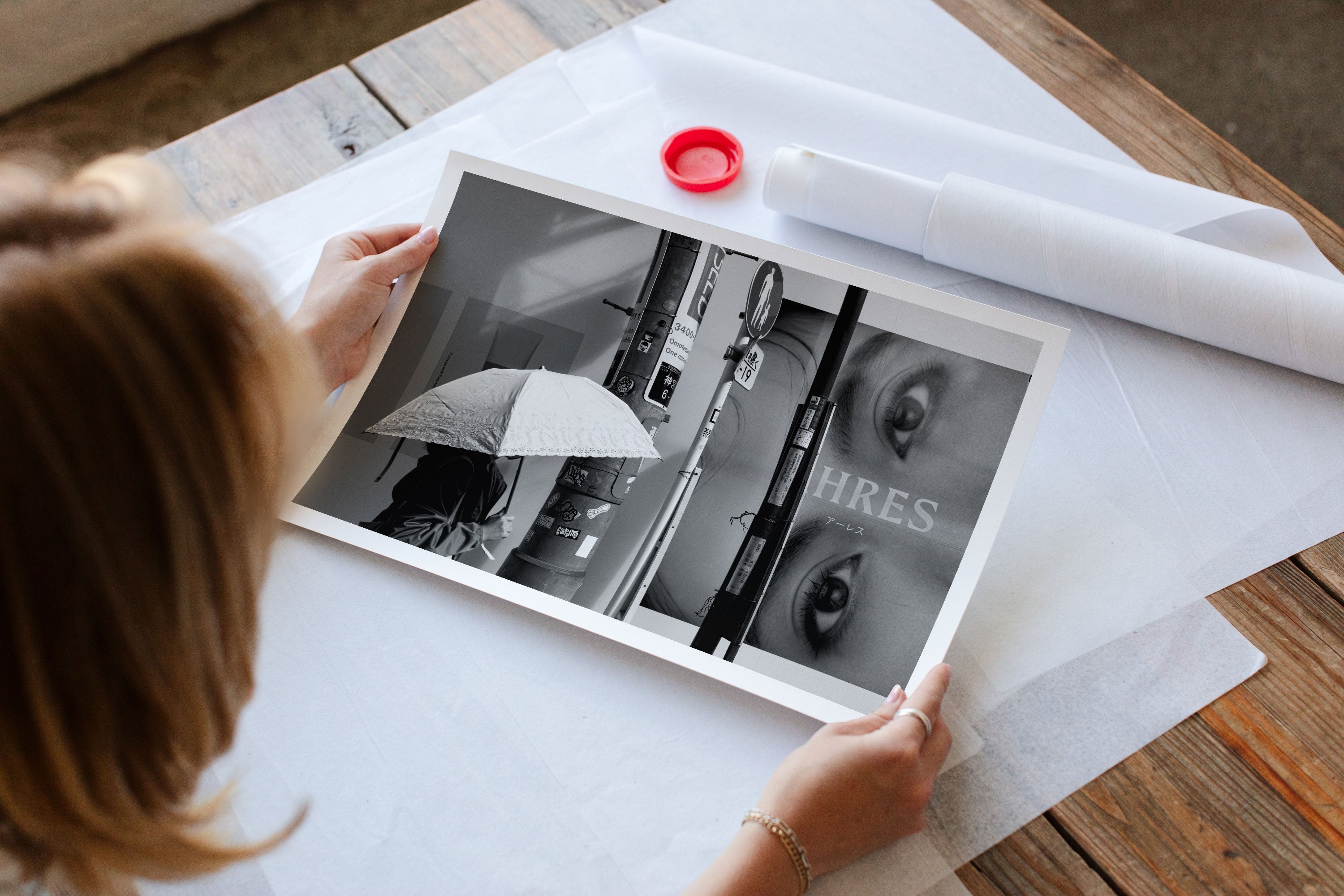 A woman sitting at a desk admiring a black and white fine art photograph featuring a woman walking in Tokyo.