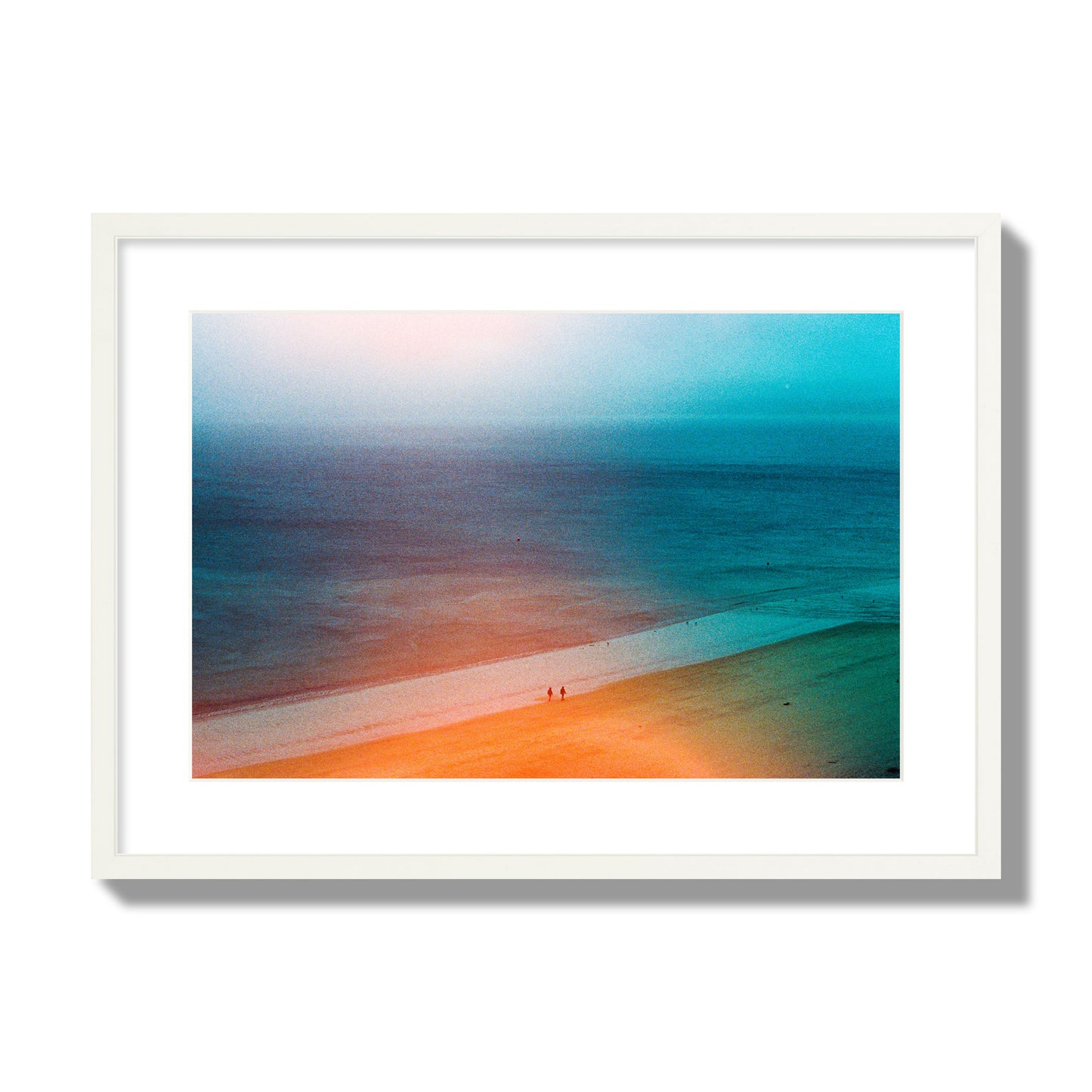 Fine art street photograph of a serene beach with two figures walking in the distance, captured in a dreamlike composition with soft orange and blue hues. Archival pigment print, large size, white frame.