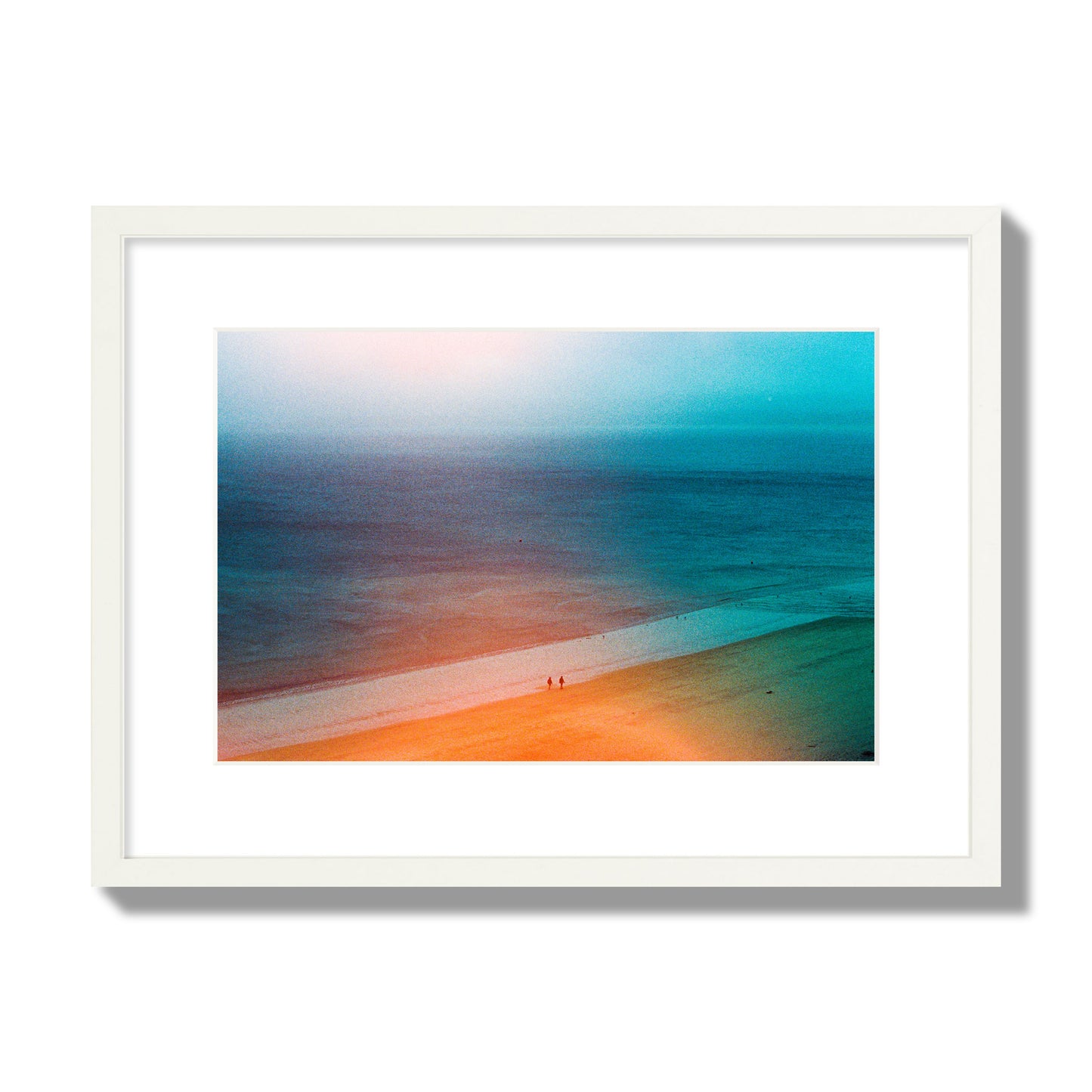 Fine art street photograph of a serene beach with two figures walking in the distance, captured in a dreamlike composition with soft orange and blue hues. Archival pigment print, medium size, white frame.