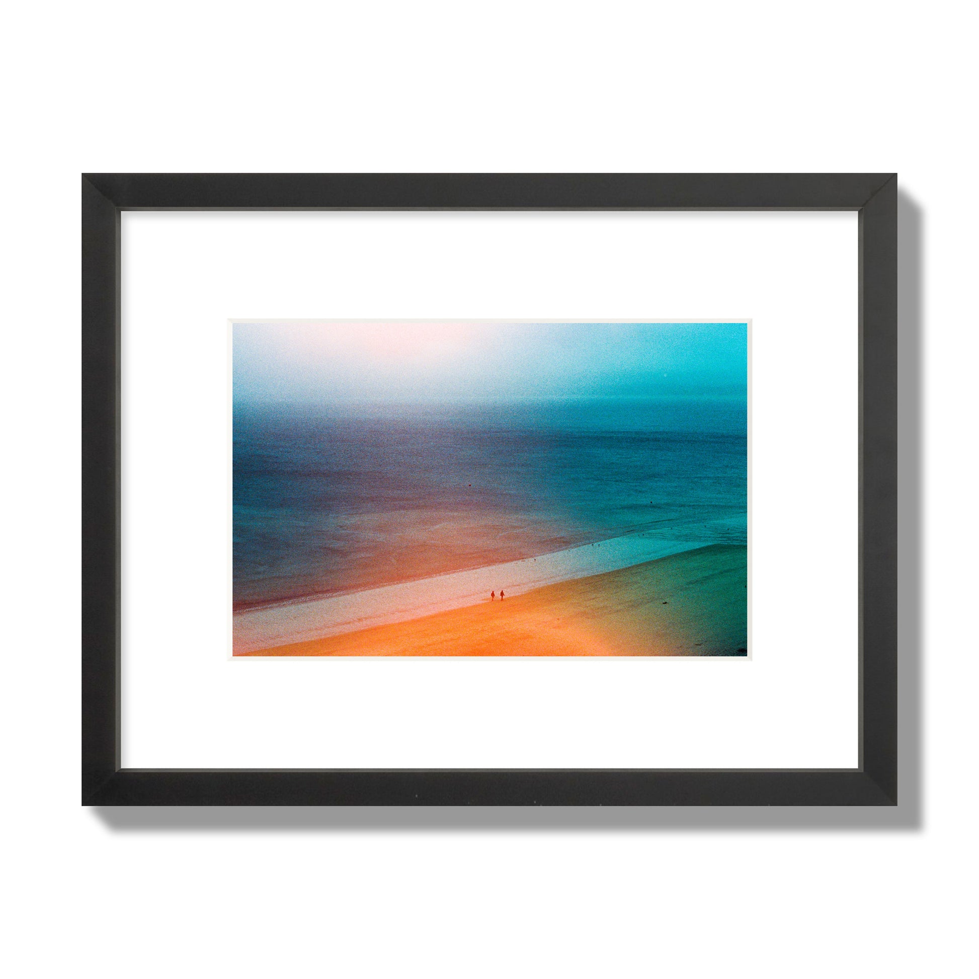 Fine art street photograph of a serene beach with two figures walking in the distance, captured in a dreamlike composition with soft orange and blue hues. Archival pigment print, small size, black frame.