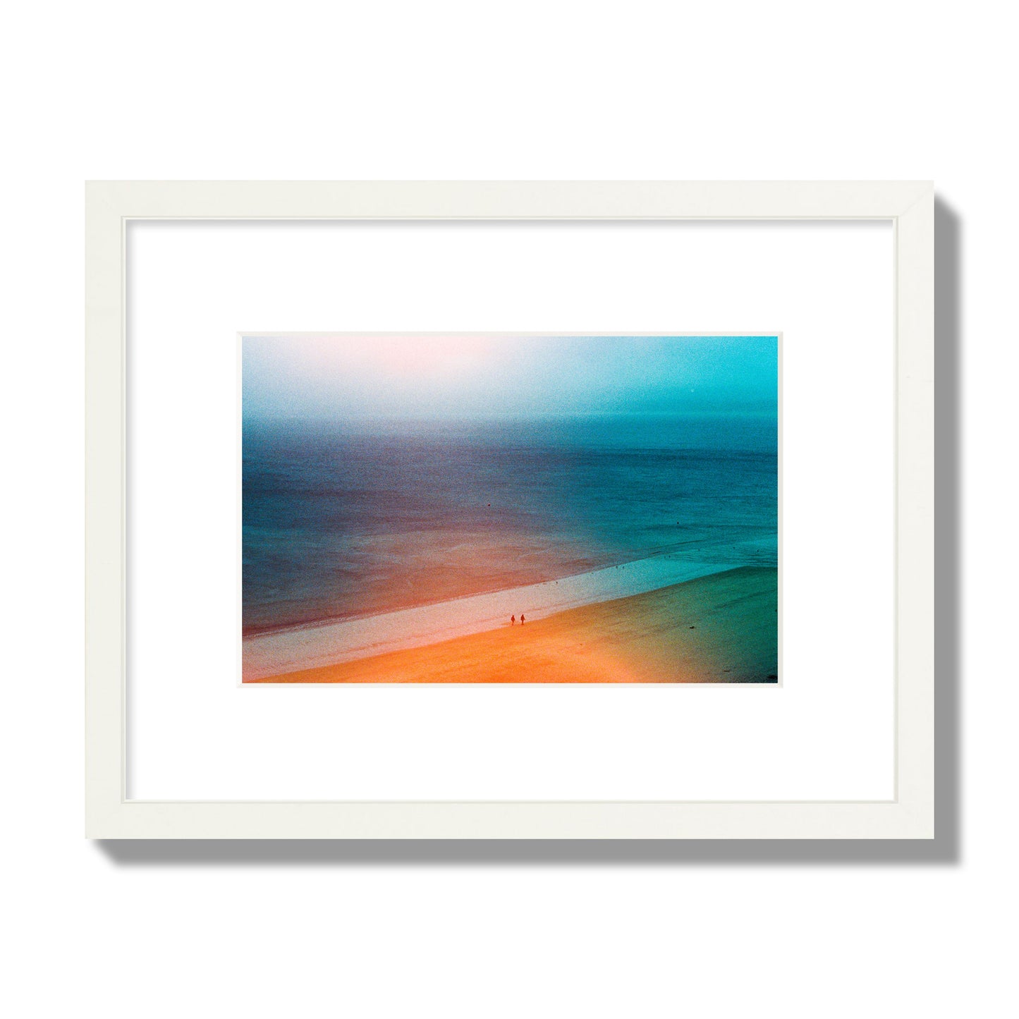 Fine art street photograph of a serene beach with two figures walking in the distance, captured in a dreamlike composition with soft orange and blue hues. Archival pigment print, small size, white frame.