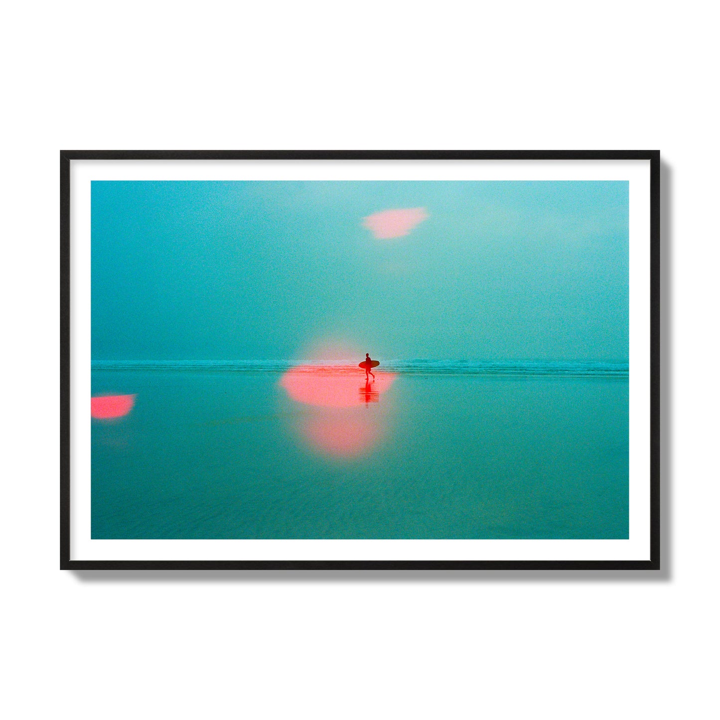 Fine art street photograph of a tranquil beach with a surfer running toward the waves, featuring a dreamlike composition with soft teal tones and a striking red lens flare. Archival pigment print, collector size, black frame.