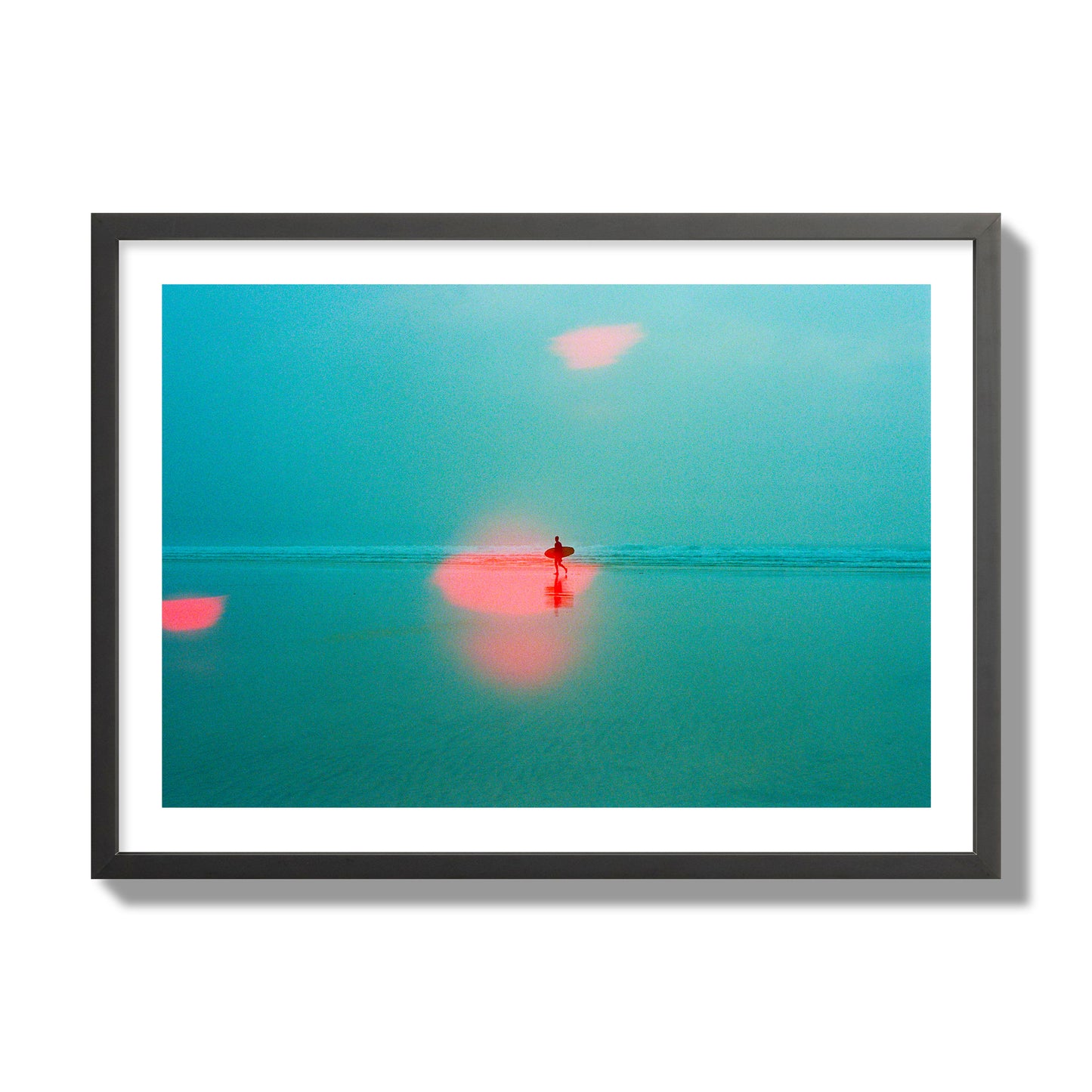 Fine art street photograph of a tranquil beach with a surfer running toward the waves, featuring a dreamlike composition with soft teal tones and a striking red lens flare. Archival pigment print, giant size, black frame.