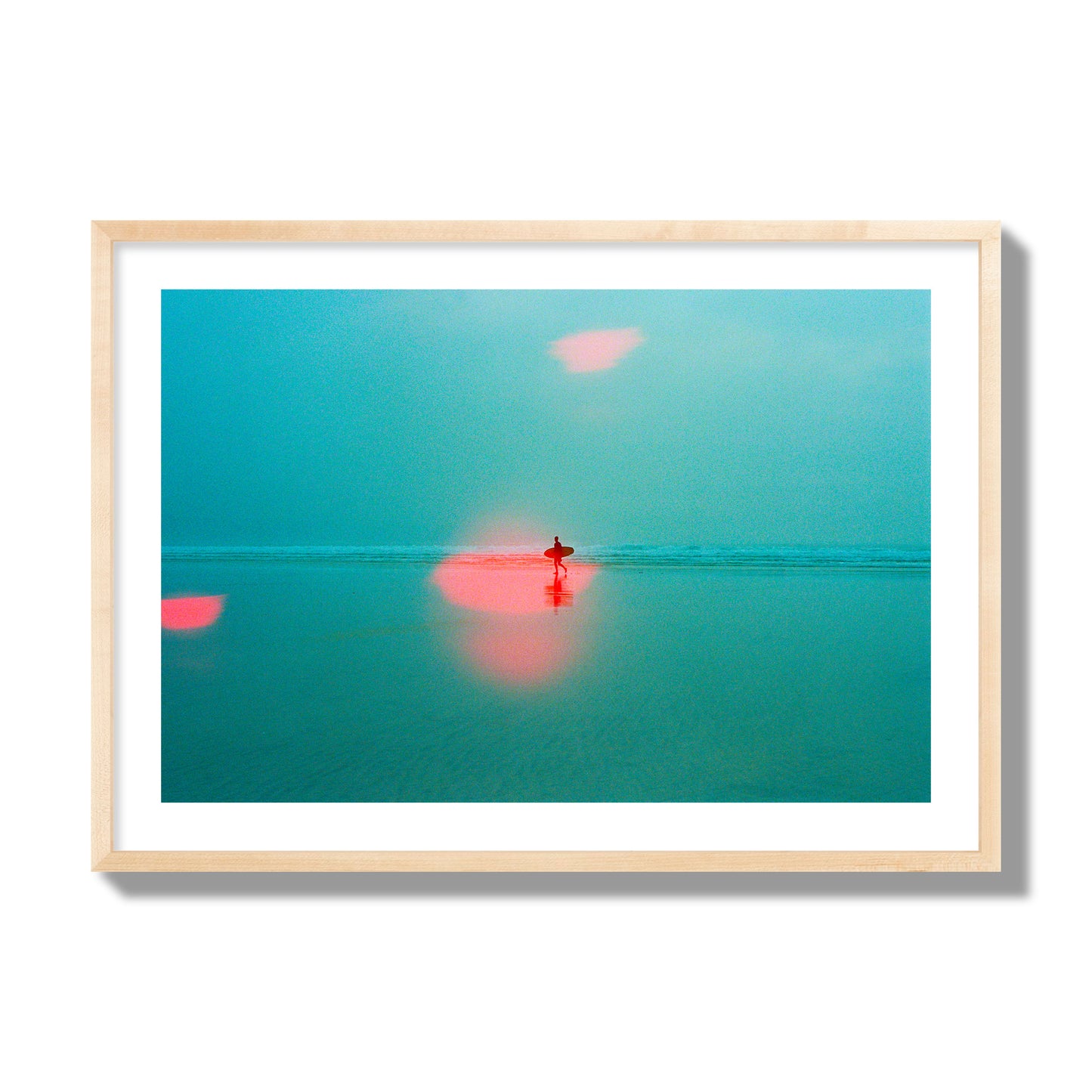 Fine art street photograph of a tranquil beach with a surfer running toward the waves, featuring a dreamlike composition with soft teal tones and a striking red lens flare. Archival pigment print, giant size, natural wood frame.