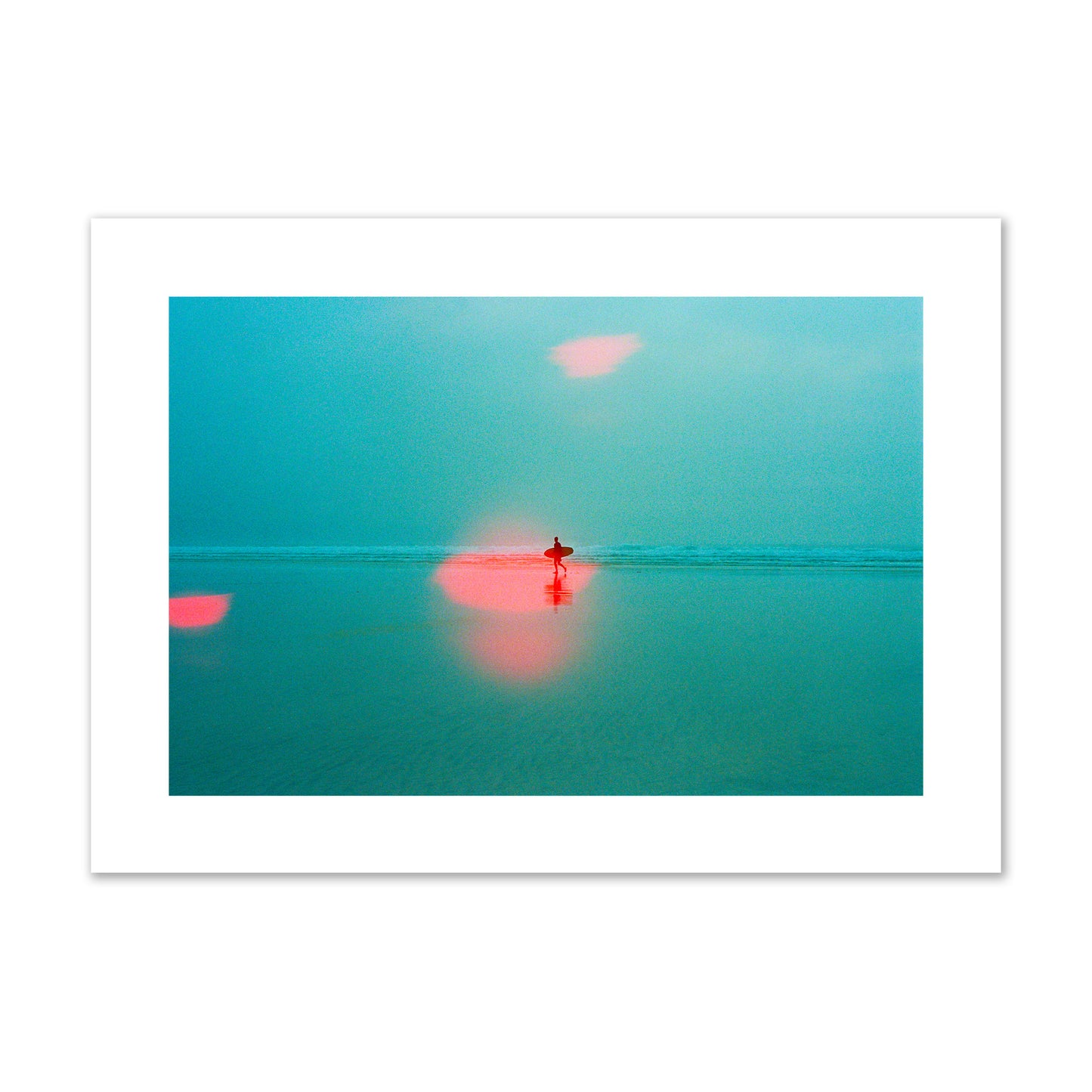 Fine art street photograph of a tranquil beach with a surfer running toward the waves, featuring a dreamlike composition with soft teal tones and a striking red lens flare. Archival pigment print, giant size, unframed.