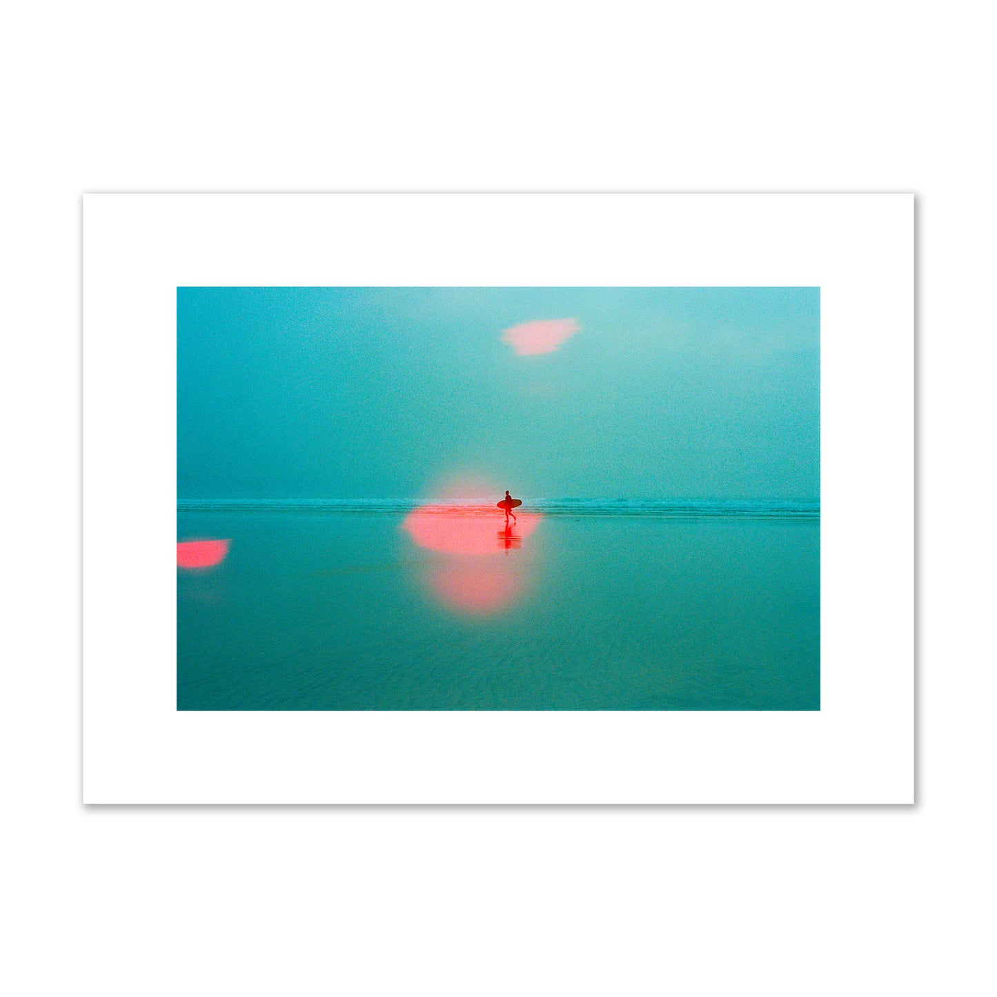 Fine art street photograph of a tranquil beach with a surfer running toward the waves, featuring a dreamlike composition with soft teal tones and a striking red lens flare. Archival pigment print, medium size, unframed.