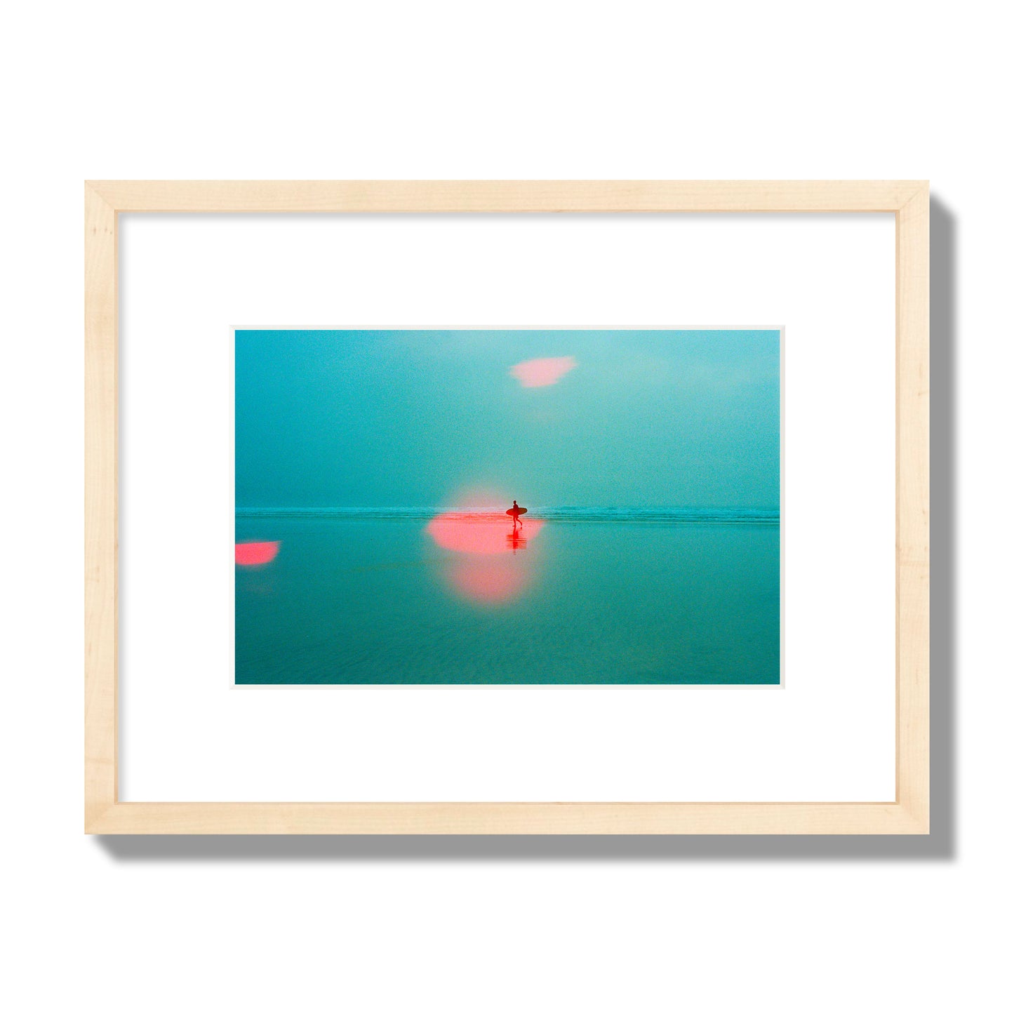 Fine art street photograph of a tranquil beach with a surfer running toward the waves, featuring a dreamlike composition with soft teal tones and a striking red lens flare. Archival pigment print, small size, natural wood frame.