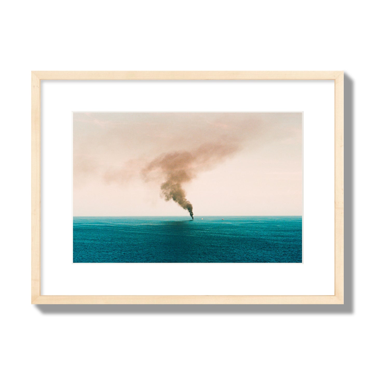 Fine art street photograph of a moody seascape with smoke rising from a distant boat, capturing a sense of mystery and atmosphere. Archival pigment print, medium size, natural wood frame.