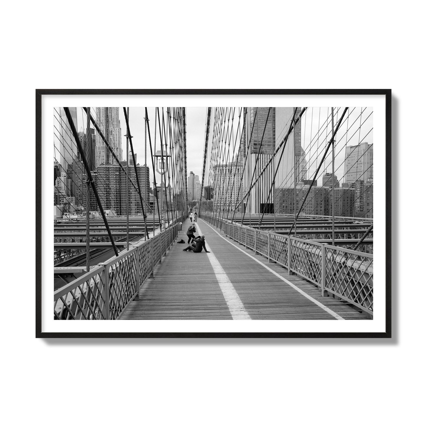 Fine art black and white photograph of a person posing on the Brooklyn Bridge with the cityscape in the background, archival pigment print, collector size, black frame