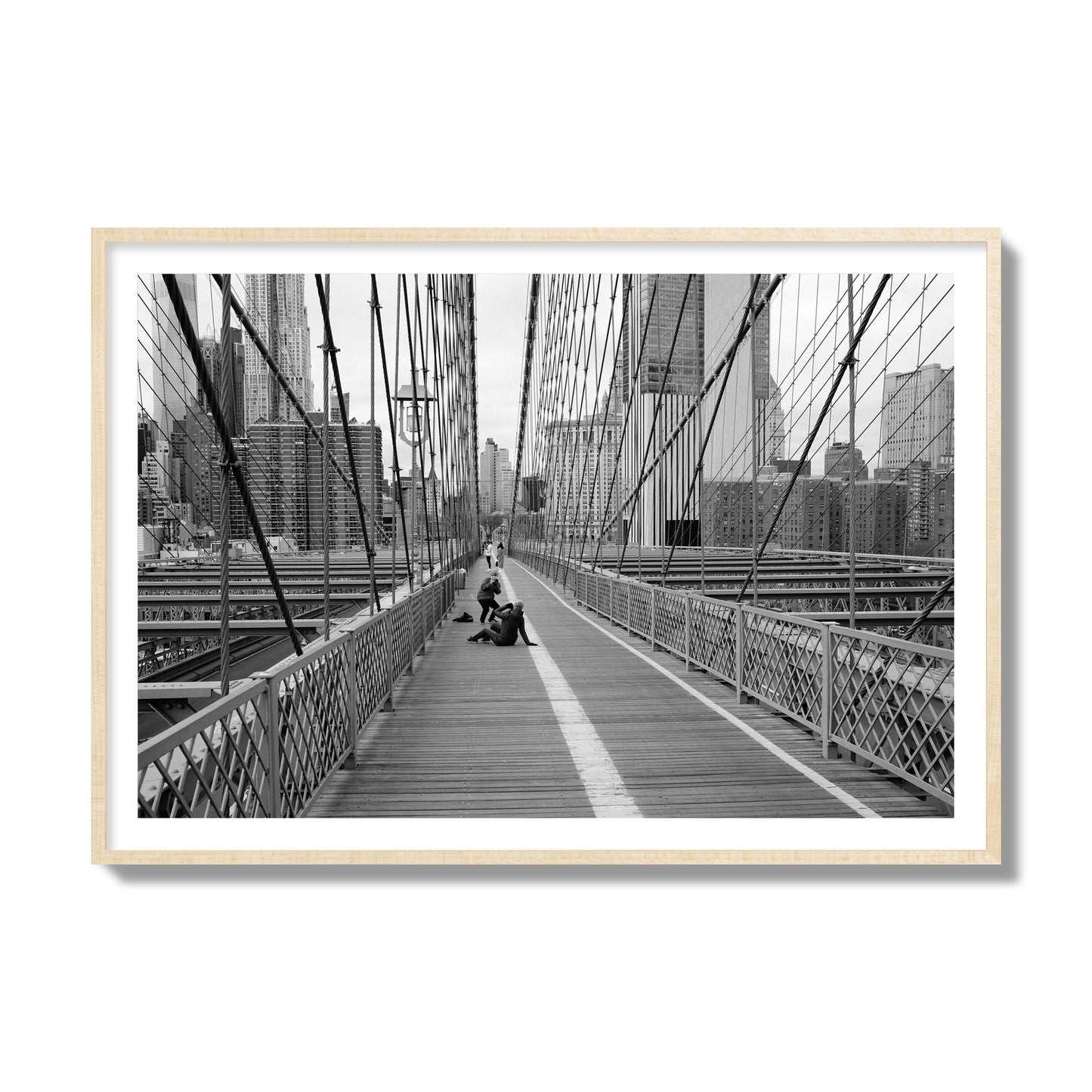 Fine art black and white photograph of a person posing on the Brooklyn Bridge with the cityscape in the background, archival pigment print, collector size, natural wood frame