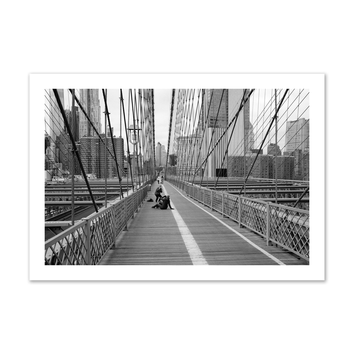 Fine art black and white photograph of a person posing on the Brooklyn Bridge with the cityscape in the background, archival pigment print, collector size, unframed
