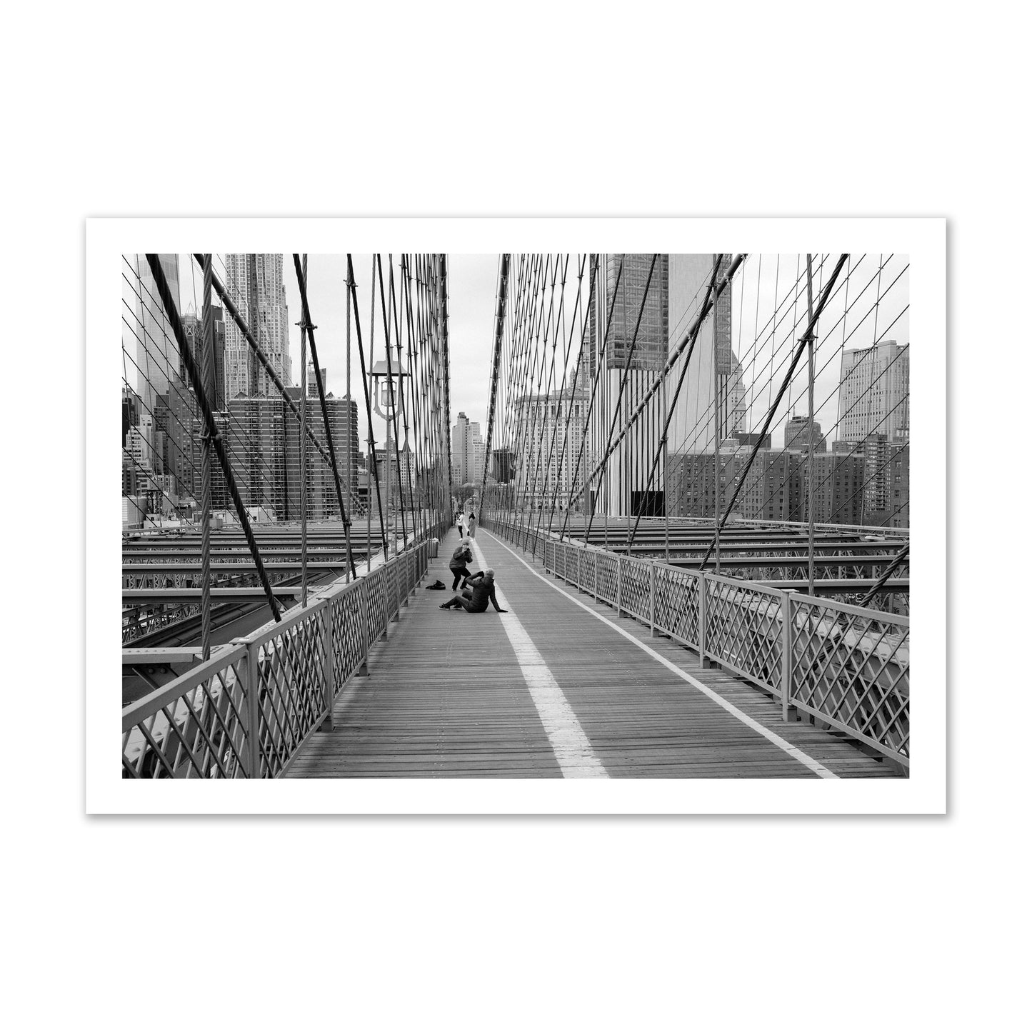 Fine art black and white photograph of a person posing on the Brooklyn Bridge with the cityscape in the background, archival pigment print, gallery size, unframed