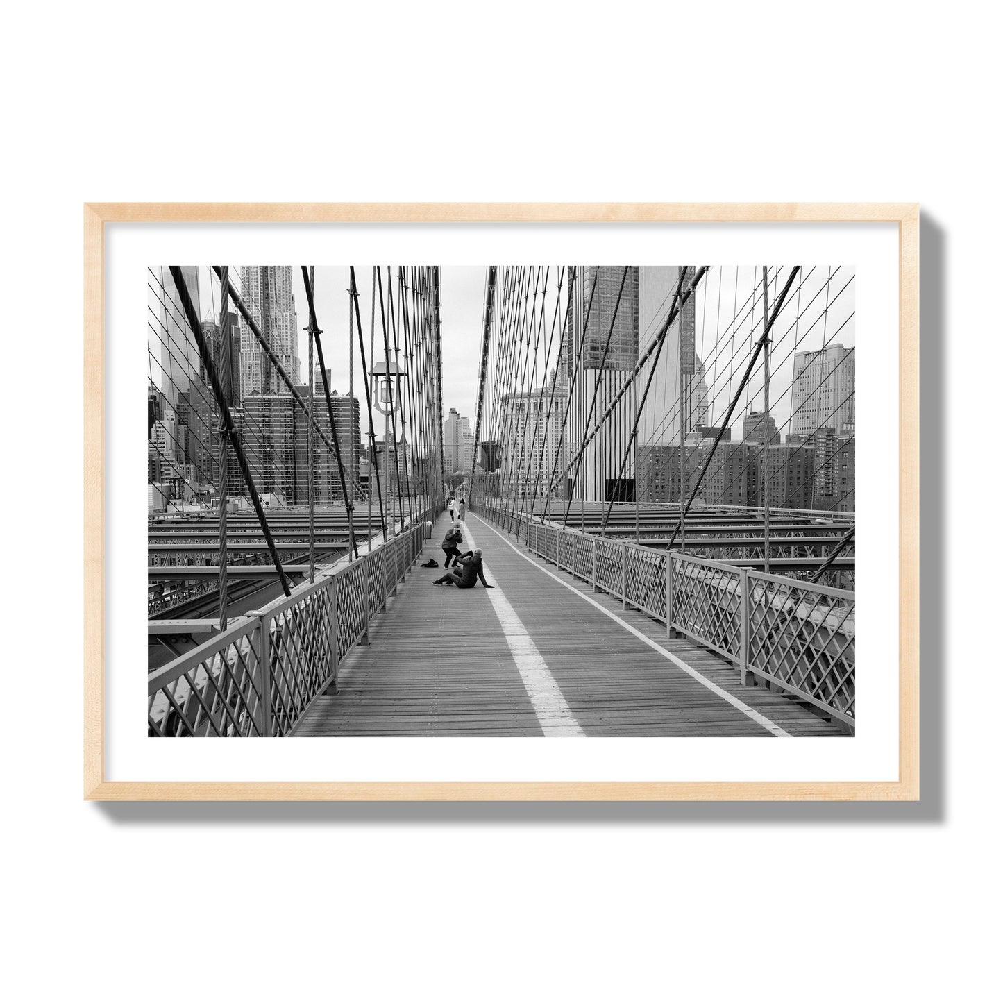 Fine art black and white photograph of a person posing on the Brooklyn Bridge with the cityscape in the background, archival pigment print, giant size, natural wood frame