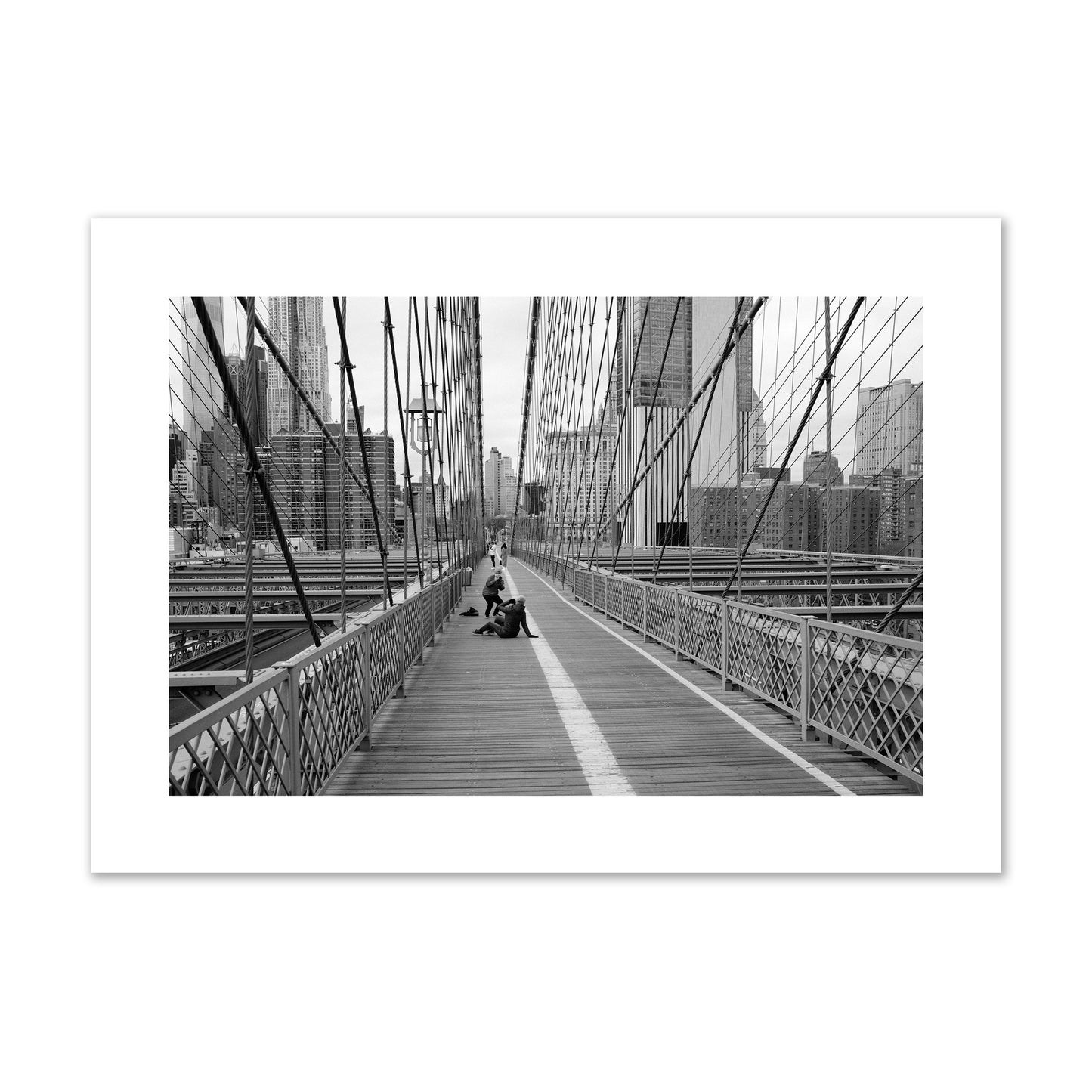 Fine art black and white photograph of a person posing on the Brooklyn Bridge with the cityscape in the background, archival pigment print, giant size, unframed