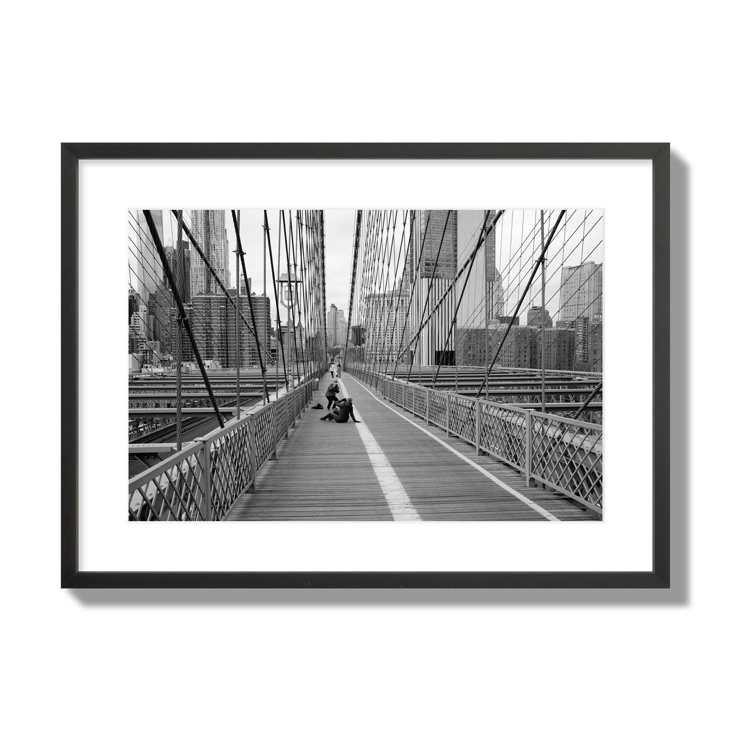 Fine art black and white photograph of a person posing on the Brooklyn Bridge with the cityscape in the background, archival pigment print, large size, black frame