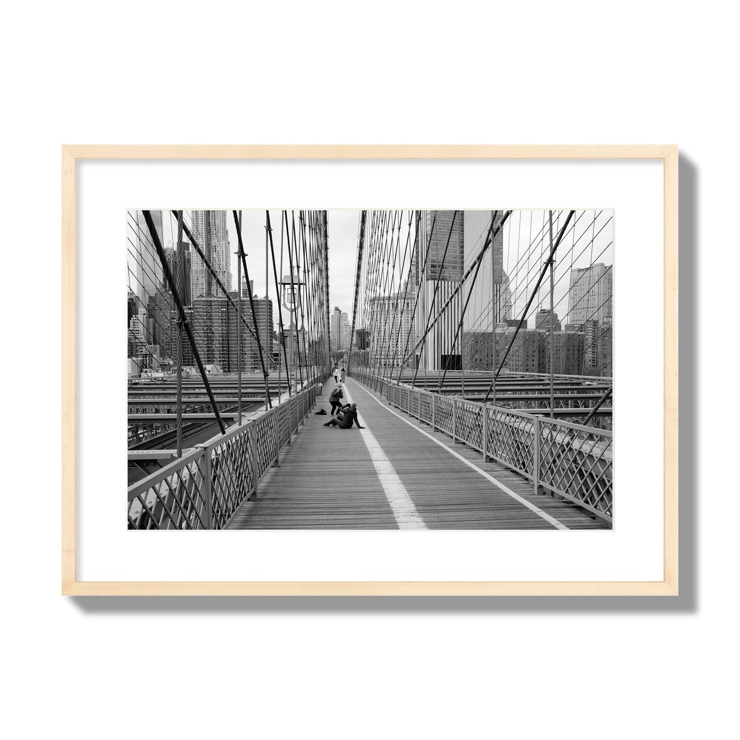 Fine art black and white photograph of a person posing on the Brooklyn Bridge with the cityscape in the background, archival pigment print, large size, natural wood frame