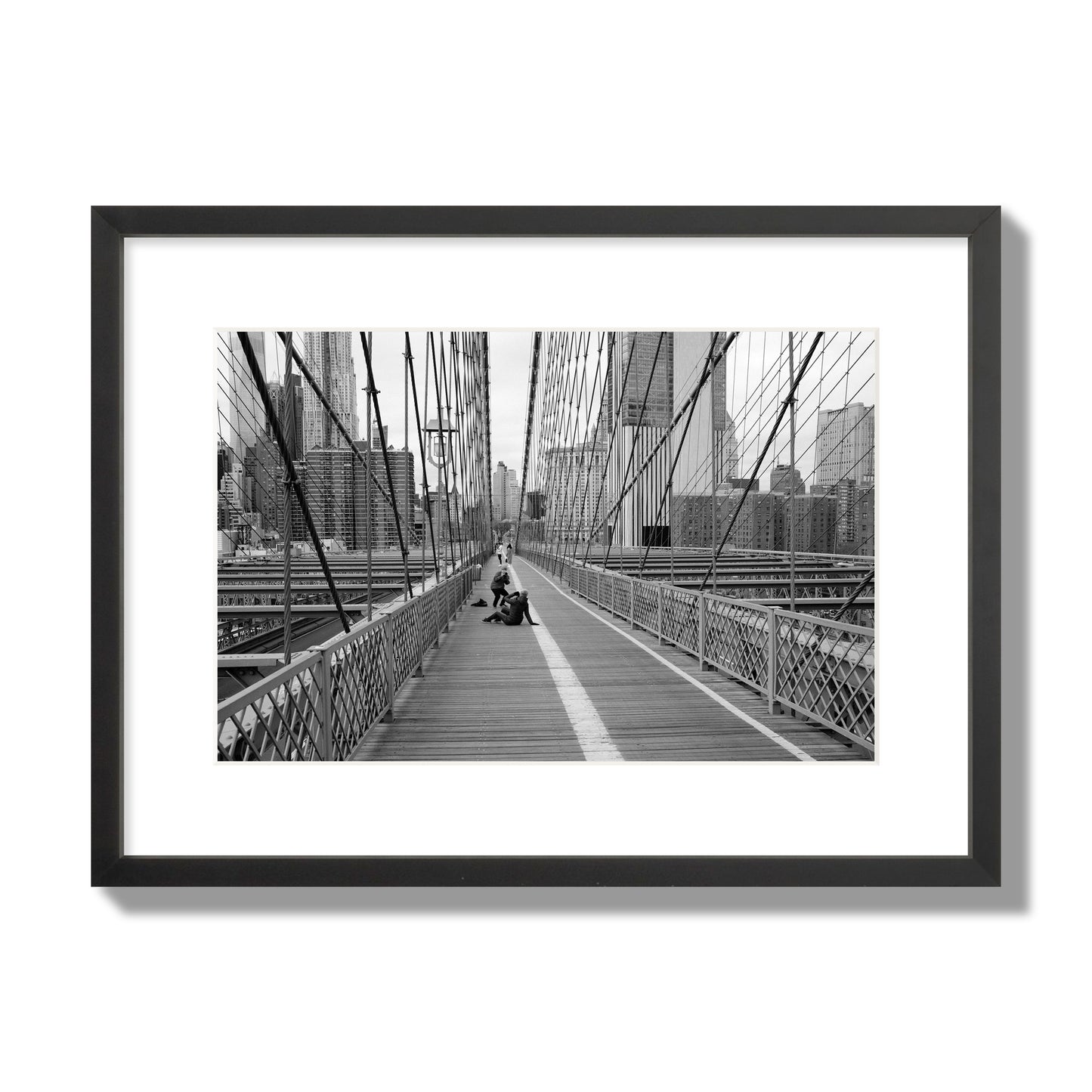 Fine art black and white photograph of a person posing on the Brooklyn Bridge with the cityscape in the background, archival pigment print, medium size, black frame