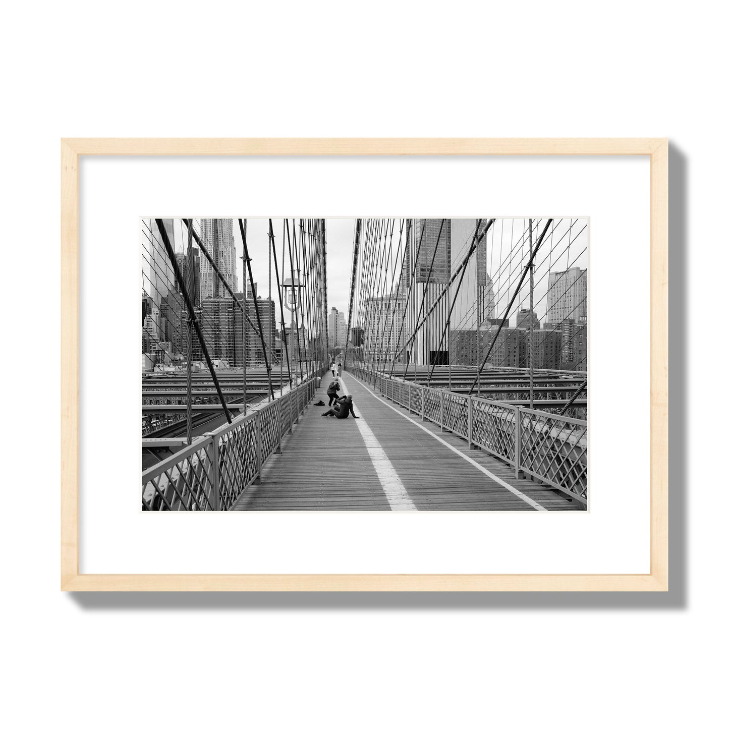 Fine art black and white photograph of a person posing on the Brooklyn Bridge with the cityscape in the background, archival pigment print, medium size, natural wood frame