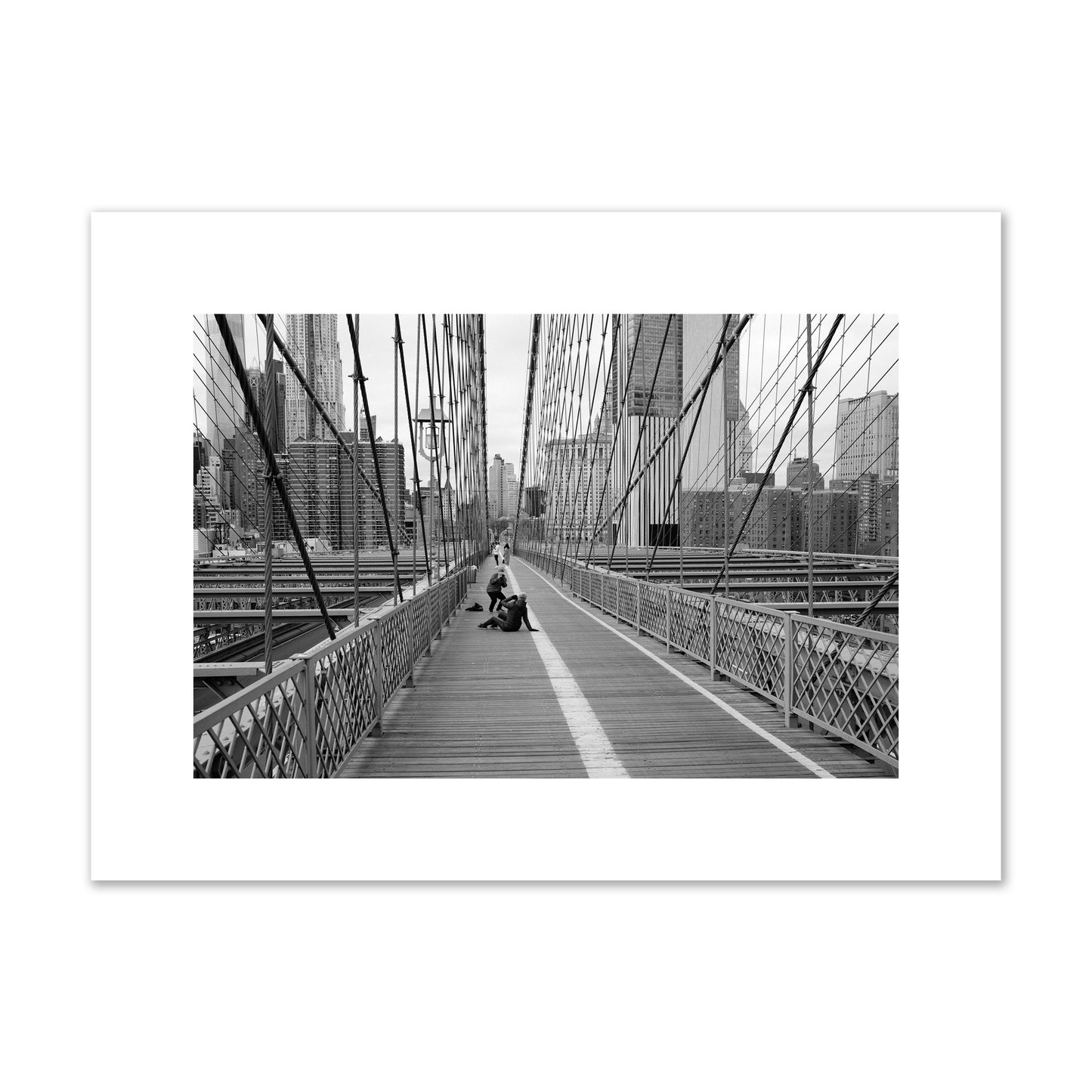 Fine art black and white photograph of a person posing on the Brooklyn Bridge with the cityscape in the background, archival pigment print, medium size, unframed