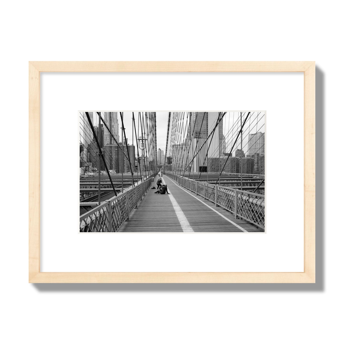 Fine art black and white photograph of a person posing on the Brooklyn Bridge with the cityscape in the background, archival pigment print, small size, natural wood frame