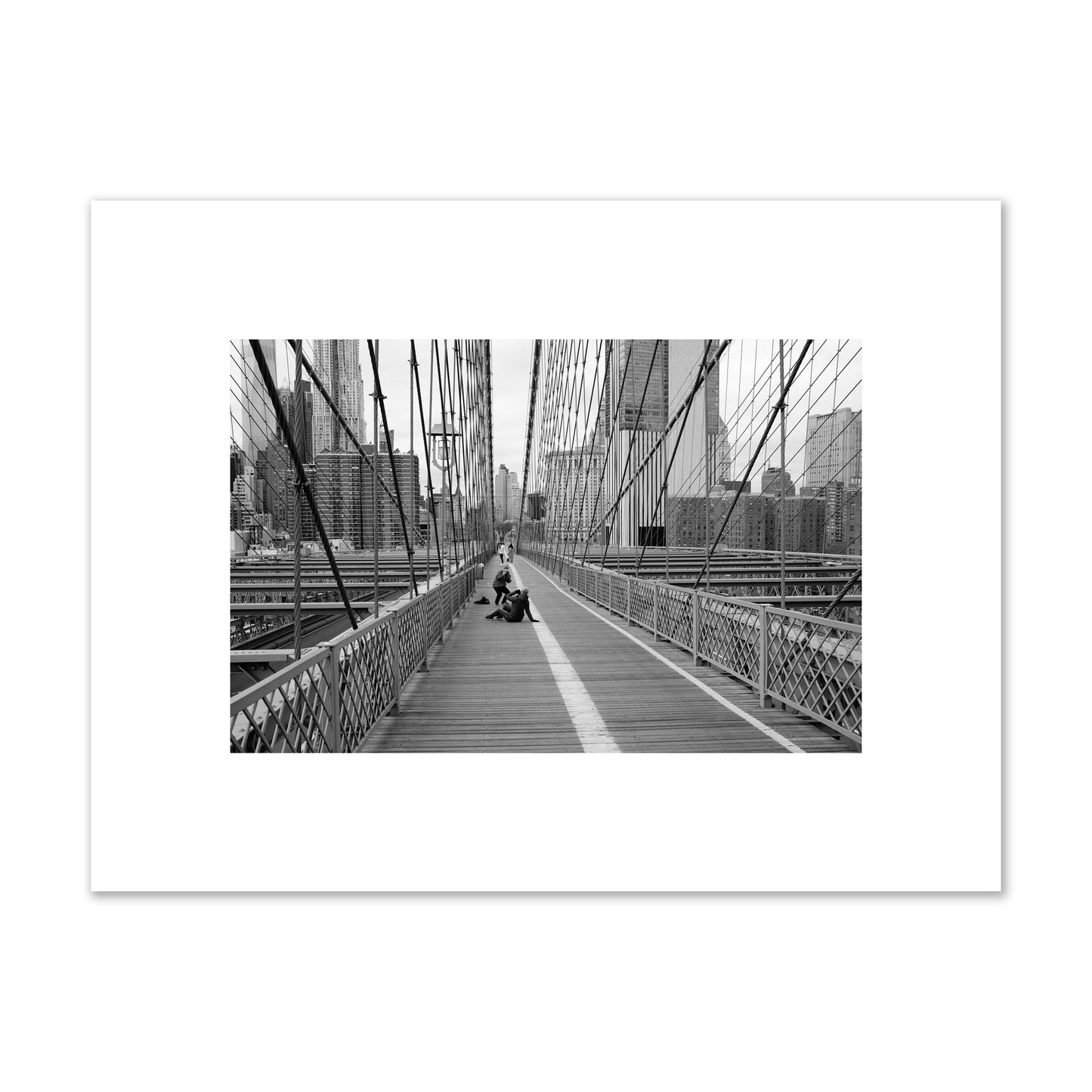 Fine art black and white photograph of a person posing on the Brooklyn Bridge with the cityscape in the background, archival pigment print, small size, unframed