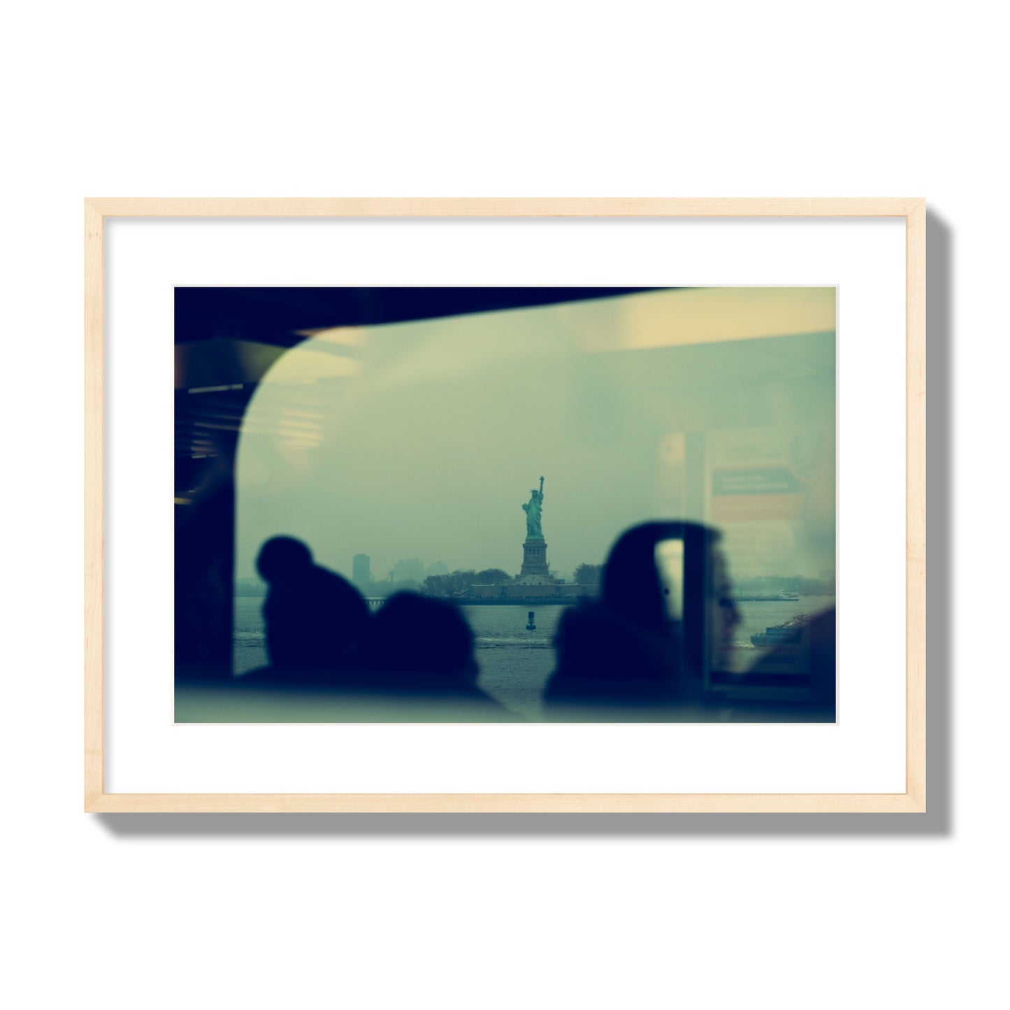 Fine art photograph of passengers silhouetted on a crowded ferry with the Statue of Liberty in the background, archival pigment print, large size, natural wood frame.