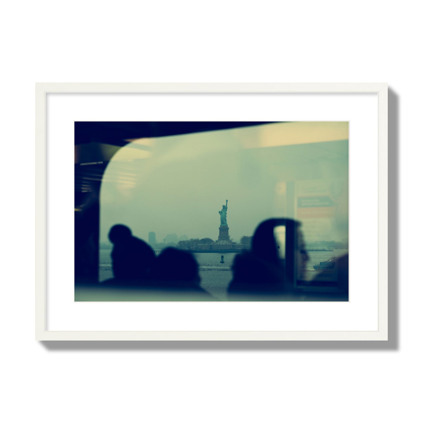 Fine art photograph of passengers silhouetted on a crowded ferry with the Statue of Liberty in the background, archival pigment print, large size, white frame.